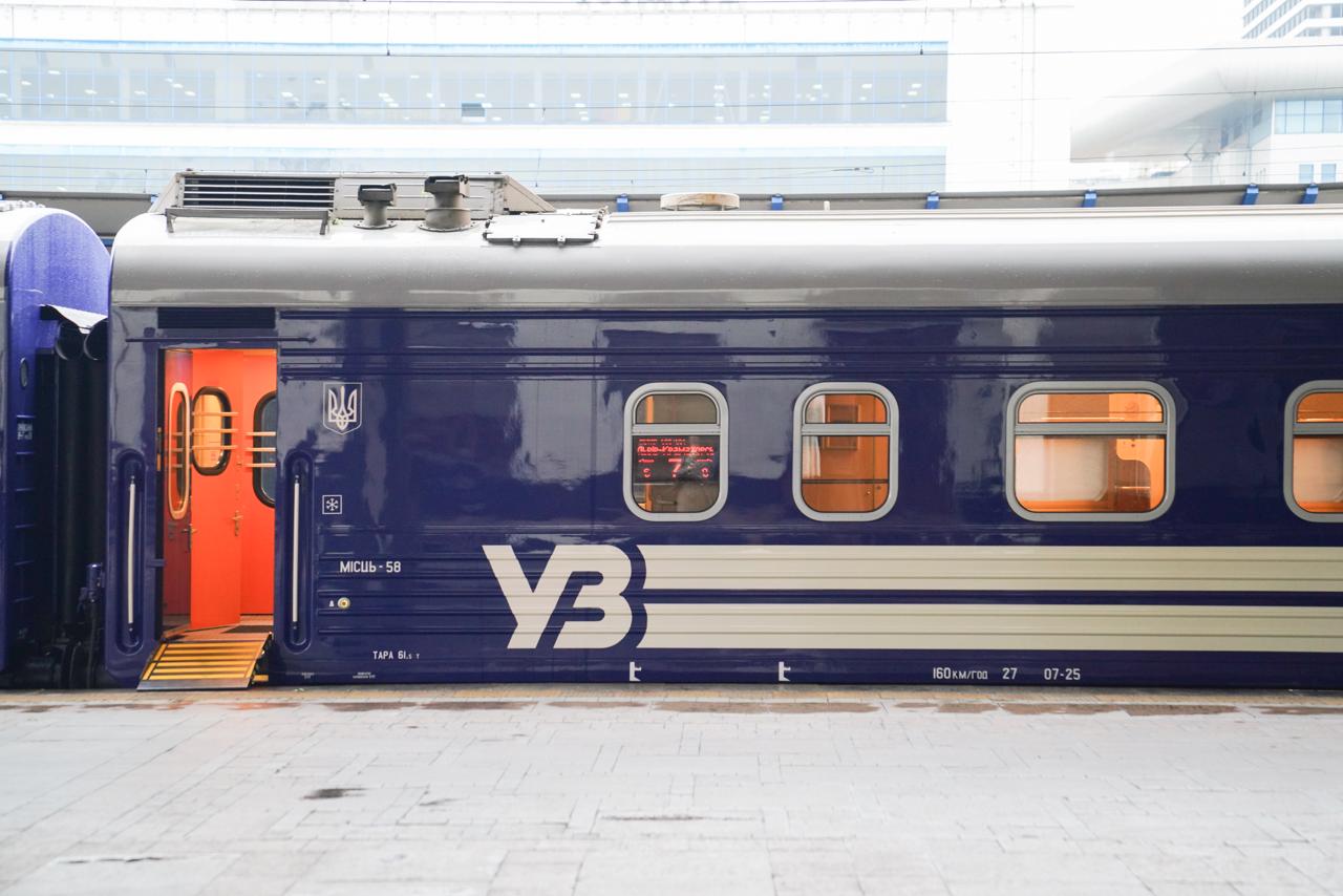 Синій пасажирський вагон «Укрзалізниці» з відчиненими дверима та логотипом УЗ на станції