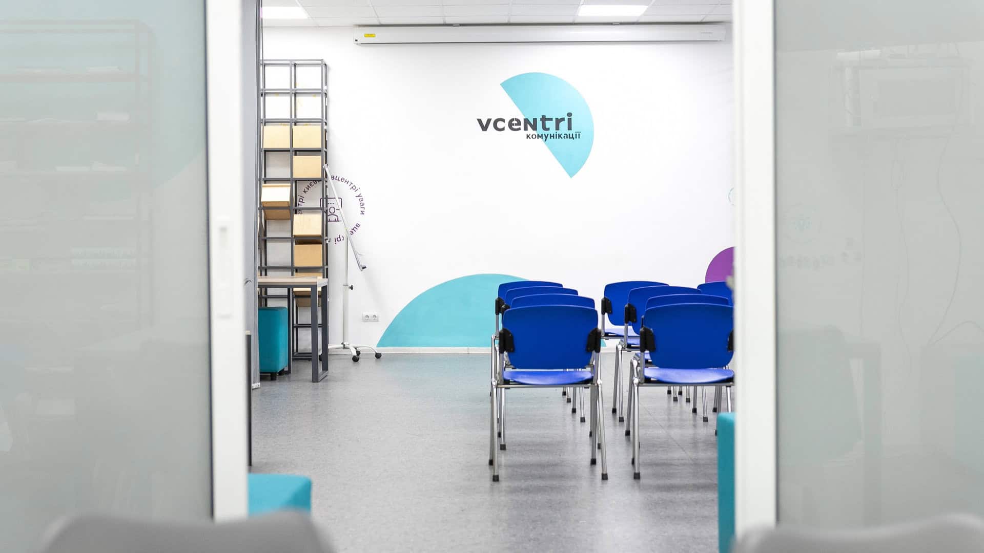 Приміщення для лекцій чи занять з білими стінами і синіми стільцями