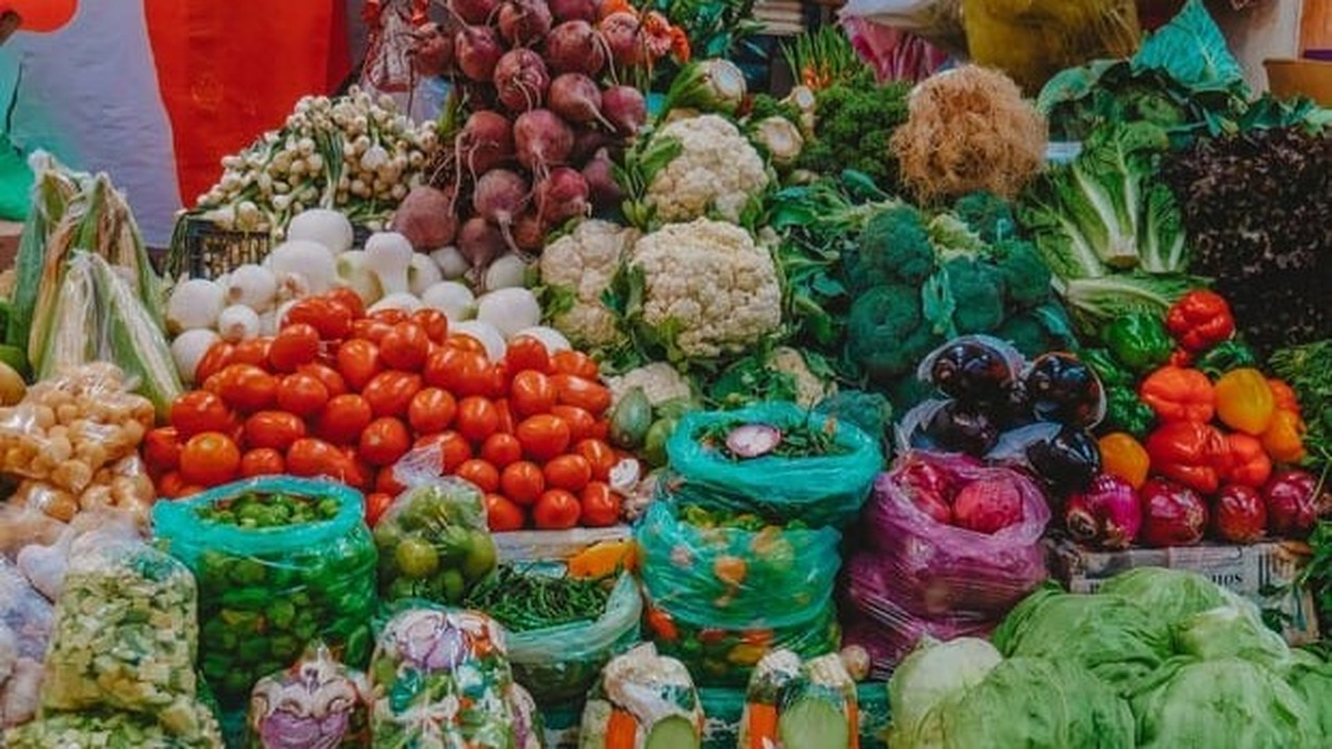 Овочі розкладені на ярмарці: помідори, цвітна капуста, зелень, броколі