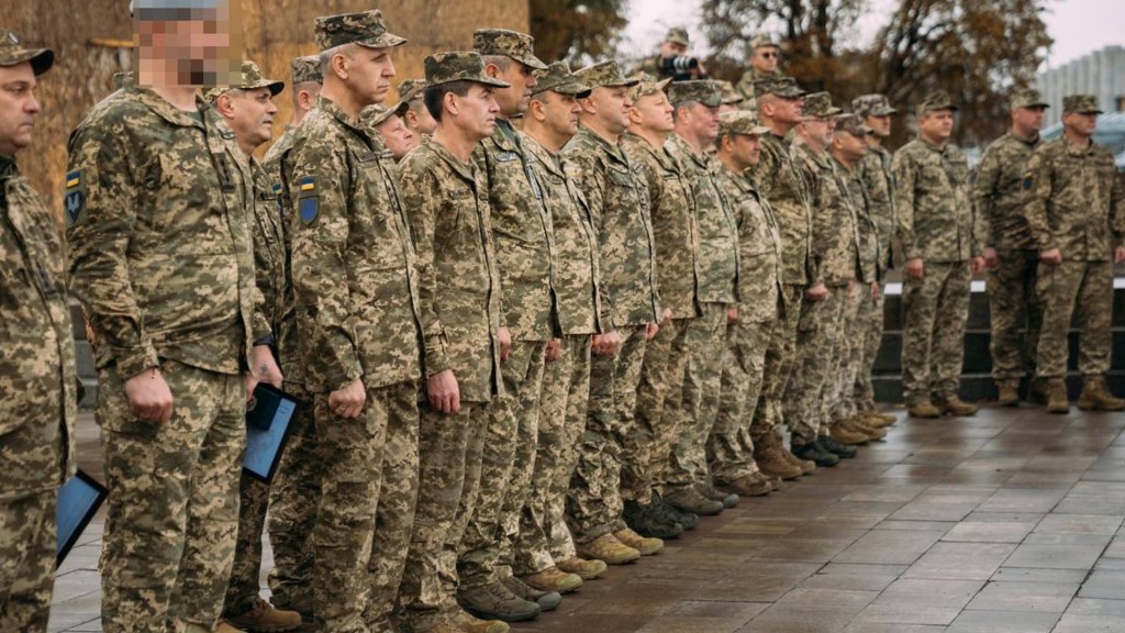 Військові на плацу стоять в шеренгу, усі у формі