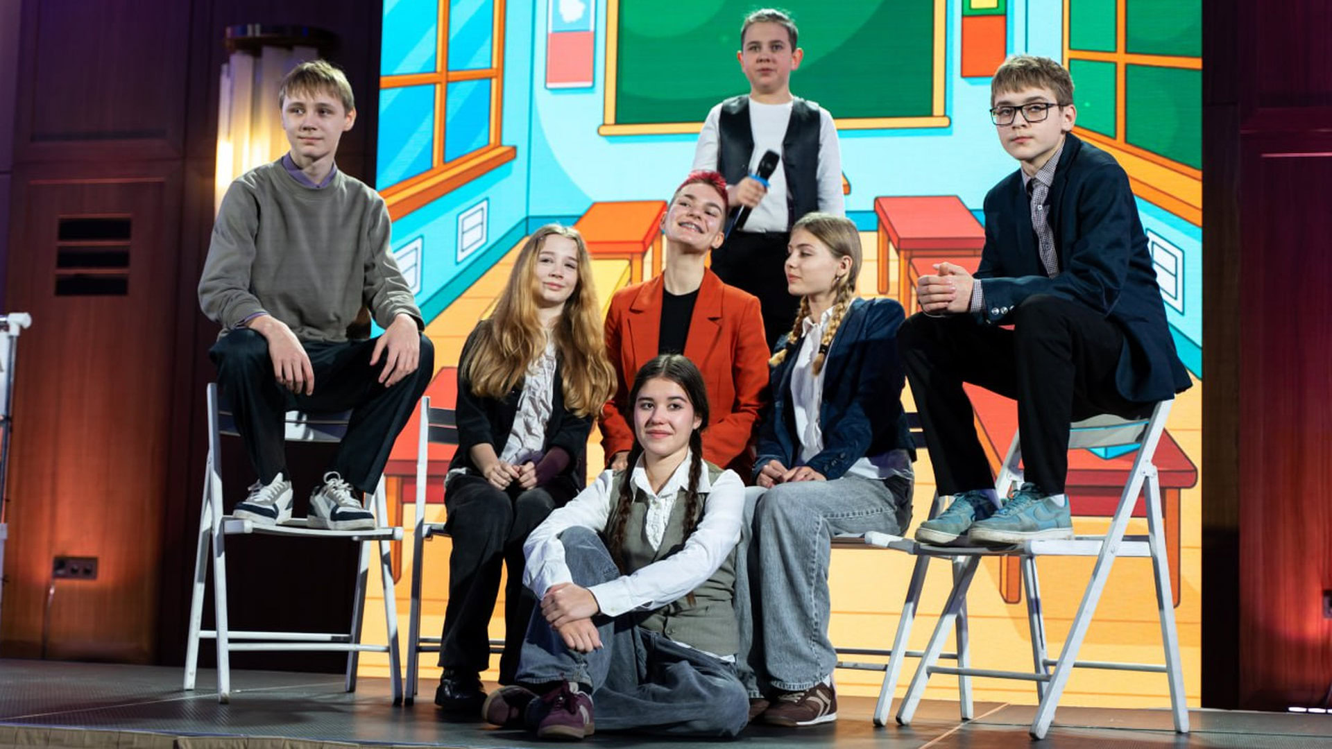 Компанія дітей гуртом сидять на сцені