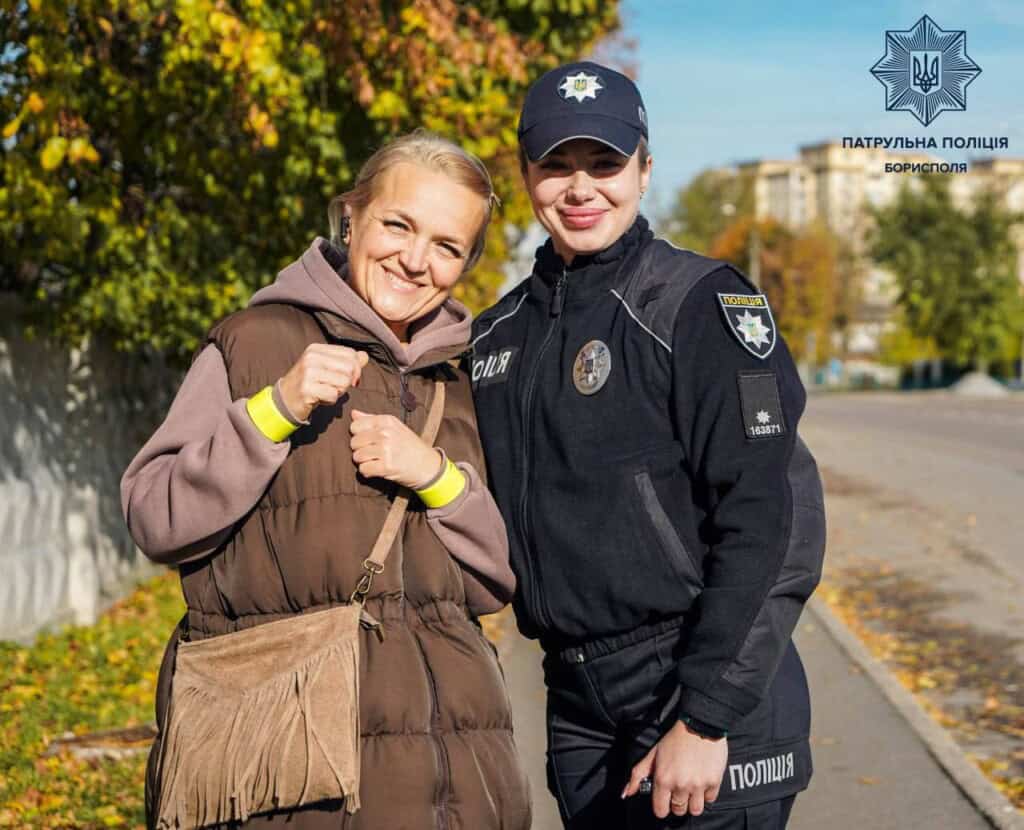 Дві жінки - поліцейська і жителька Борисполя стоять на вулиці і фотографуються із світловідбивальною стрічкою на руці у жительки Борисполя