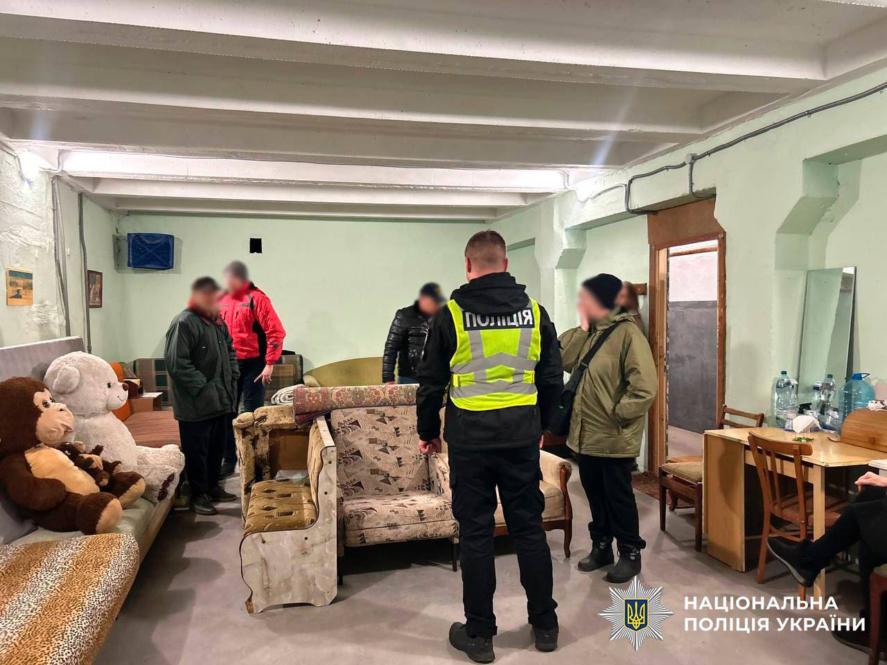 Працівники поліції стоять в кімнаті в укритті Києва, там кілька диванів, столів і іграшки