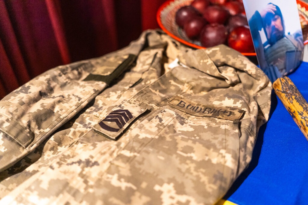 Фонд «Маємо жити» обʼєднав 26 міст України вечорами памʼяті загиблих захисників Військова форма з шевроном, поруч яблука і рамка з фото