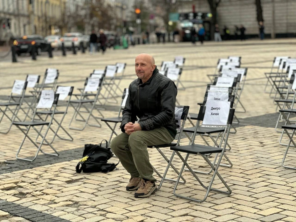 Київ вшанував 27 ув'язнених журналістів: інсталяція на Софійській площі Чоловік сидить на фоні порожніх стільців
