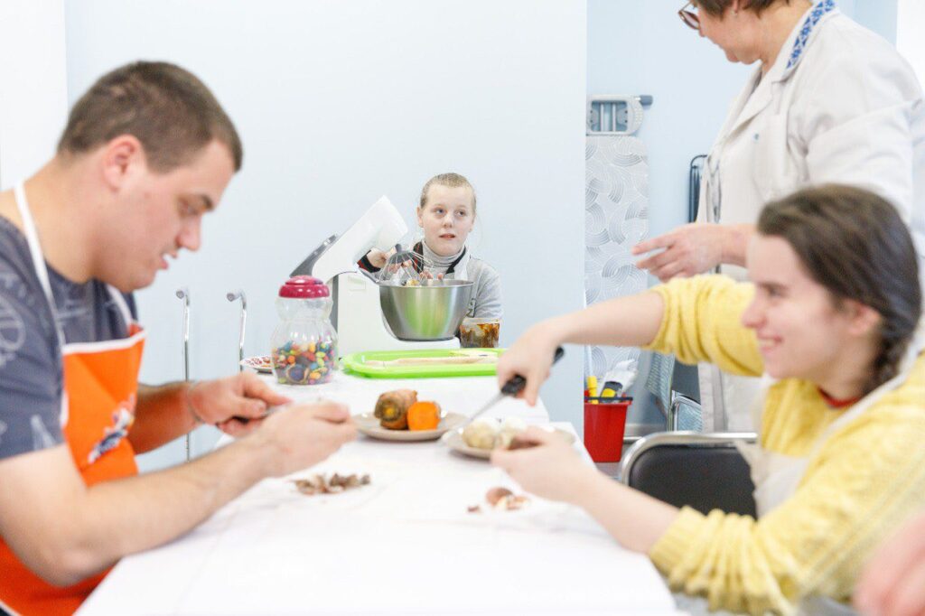 У Києві діти з інвалідністю можуть навчитись шити та гончарити Діти з інфалідністю сидять за столом і готують солодощі