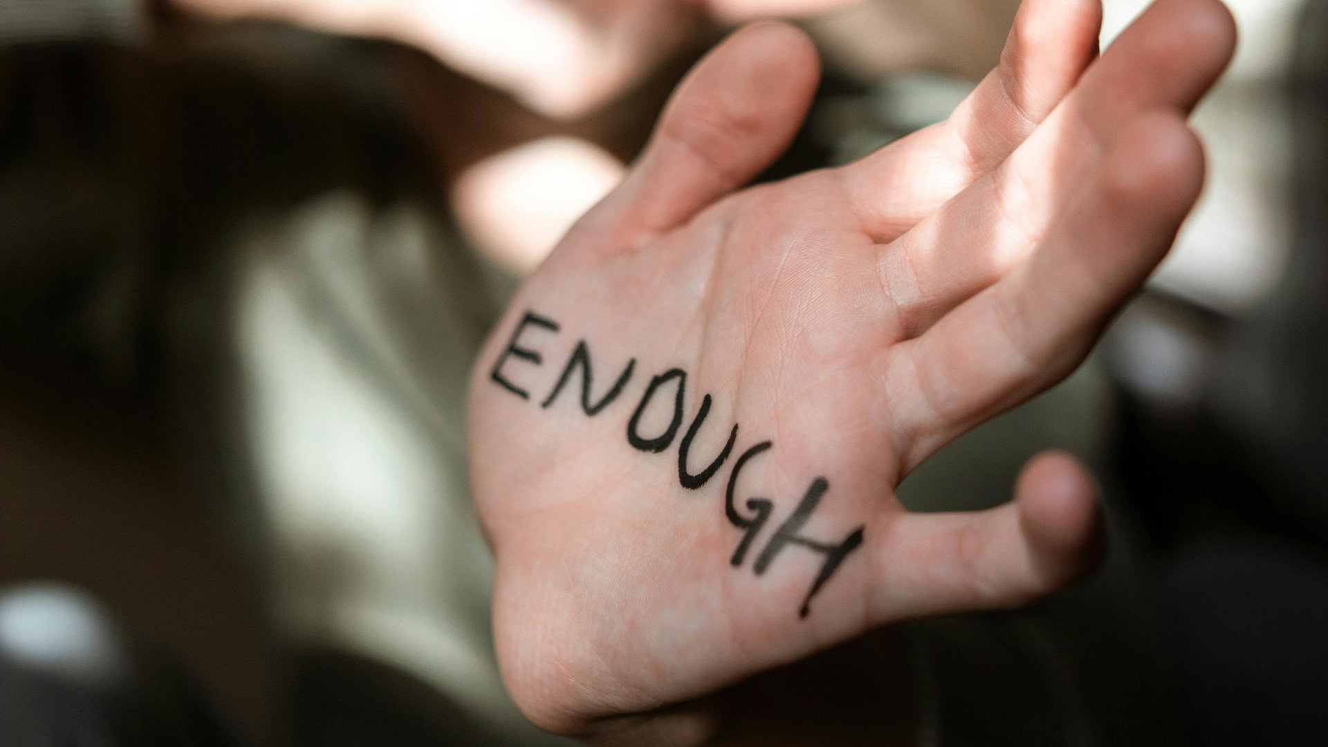 Символічне зображення боротьби із насильством — рука з написом Досить англійською мовою