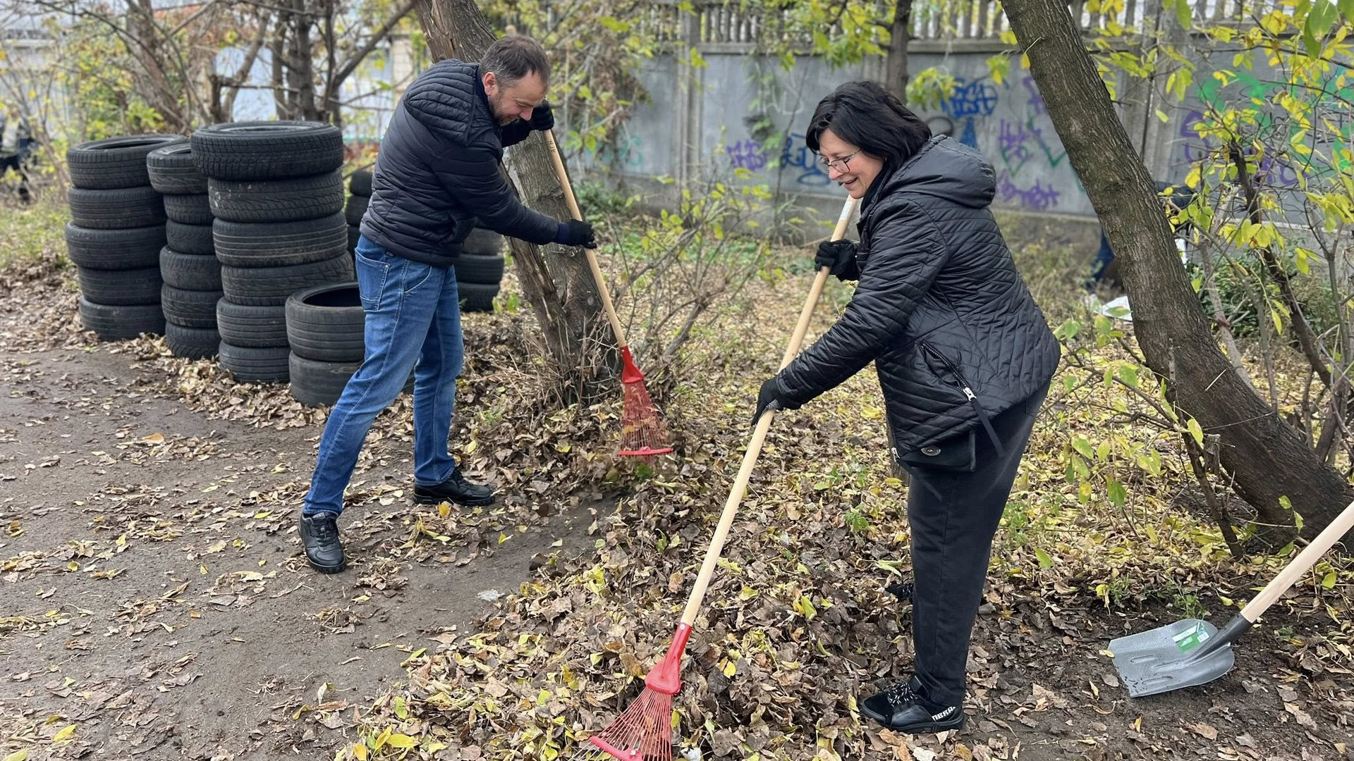 Двоє людей прибирають листя на вулиці