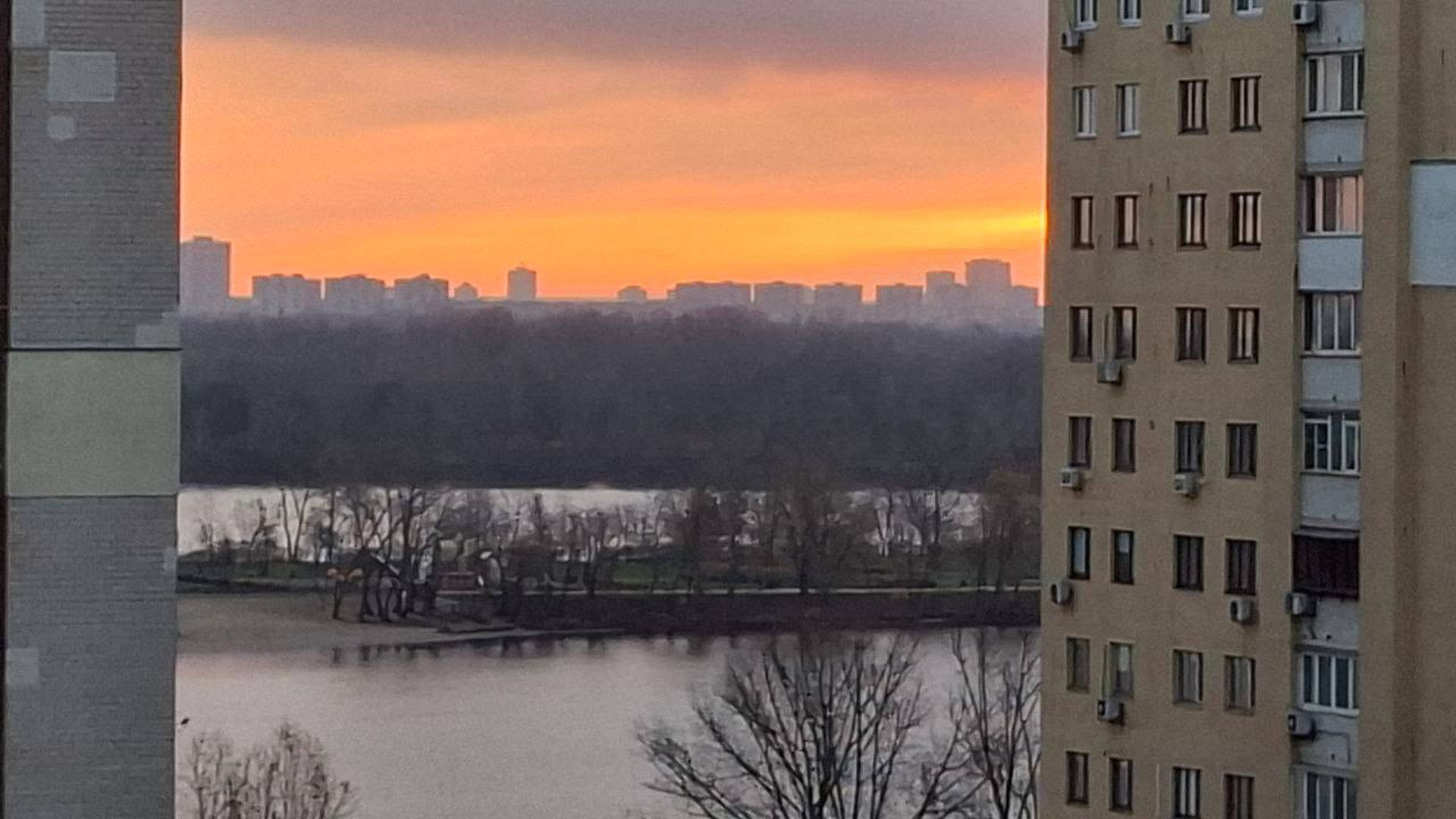 Багатоповерхівки в Києві і крізь них видно річку і світанок