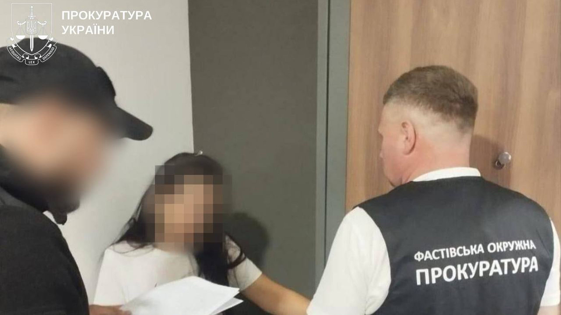 Троє людей, з них одна жінка в білій футболці і з заблюреним обличчям