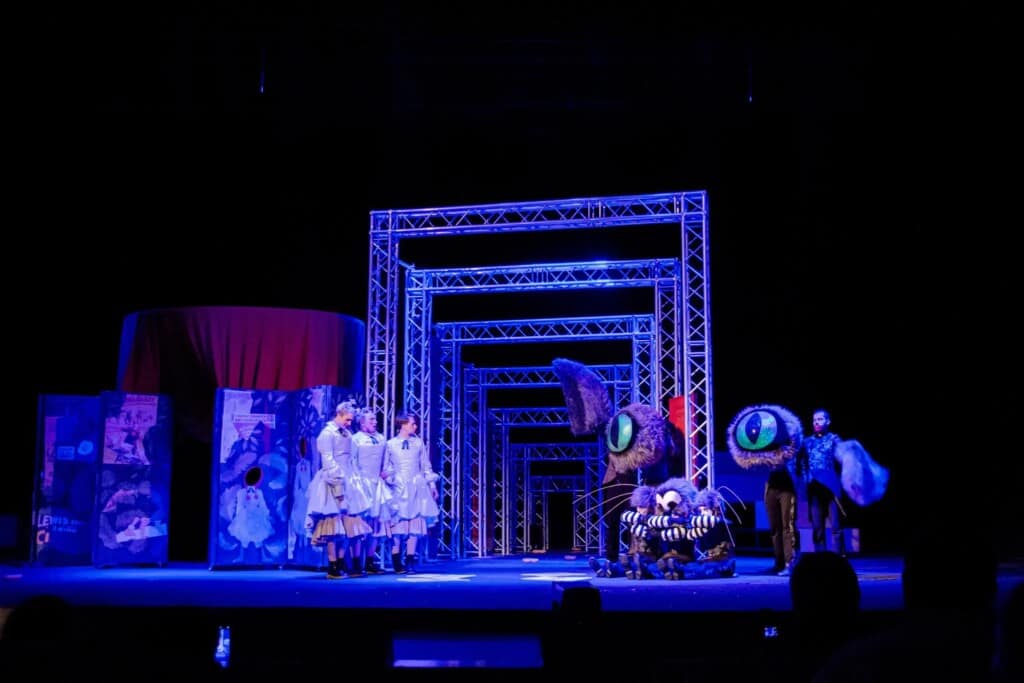 Сцена з вистави "Аліса в Дивокраї" з акторами та Чеширським котом