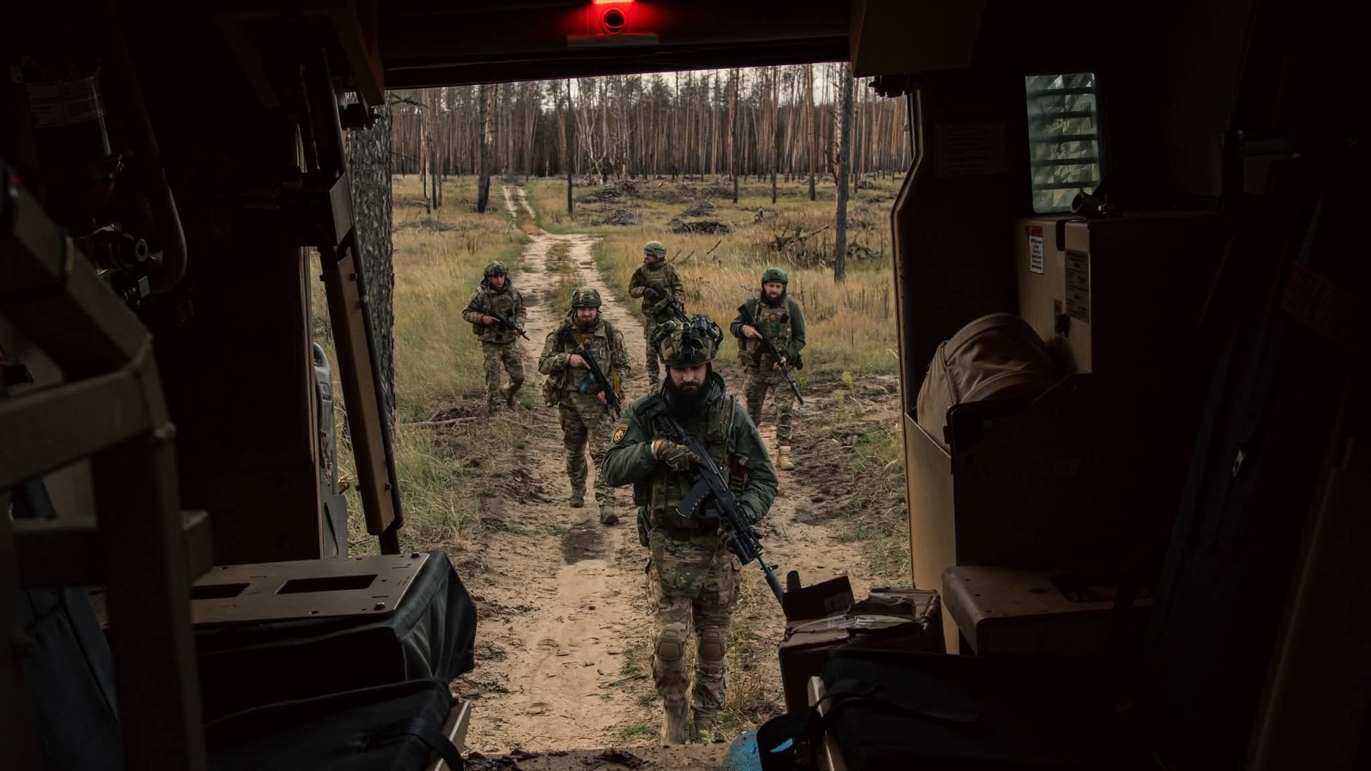 Пʼятеро військових ідуть військове авто після бойової роботи в лісосмузі