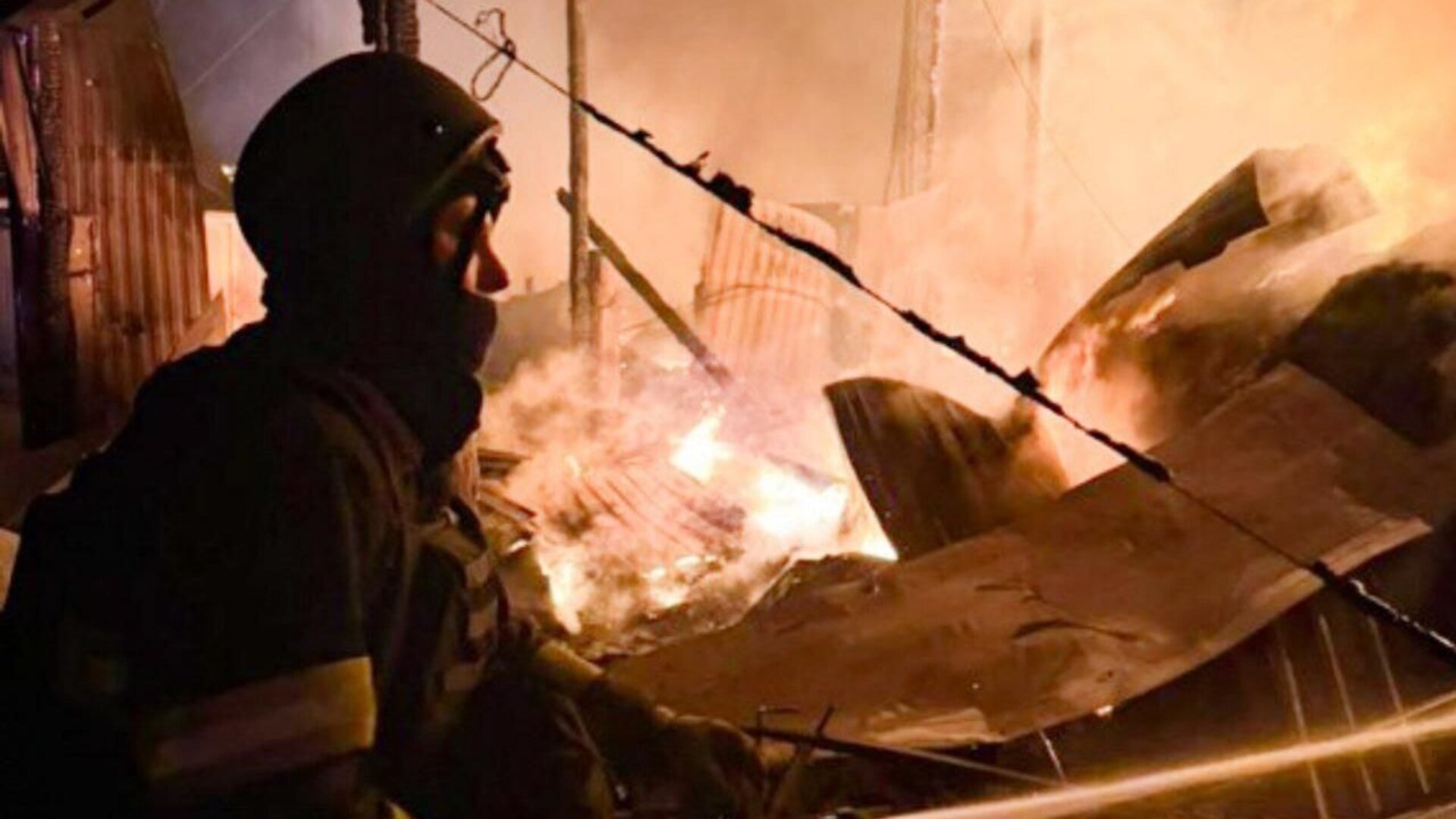 Рятувальник на тлі пожежі після російського обстрілу