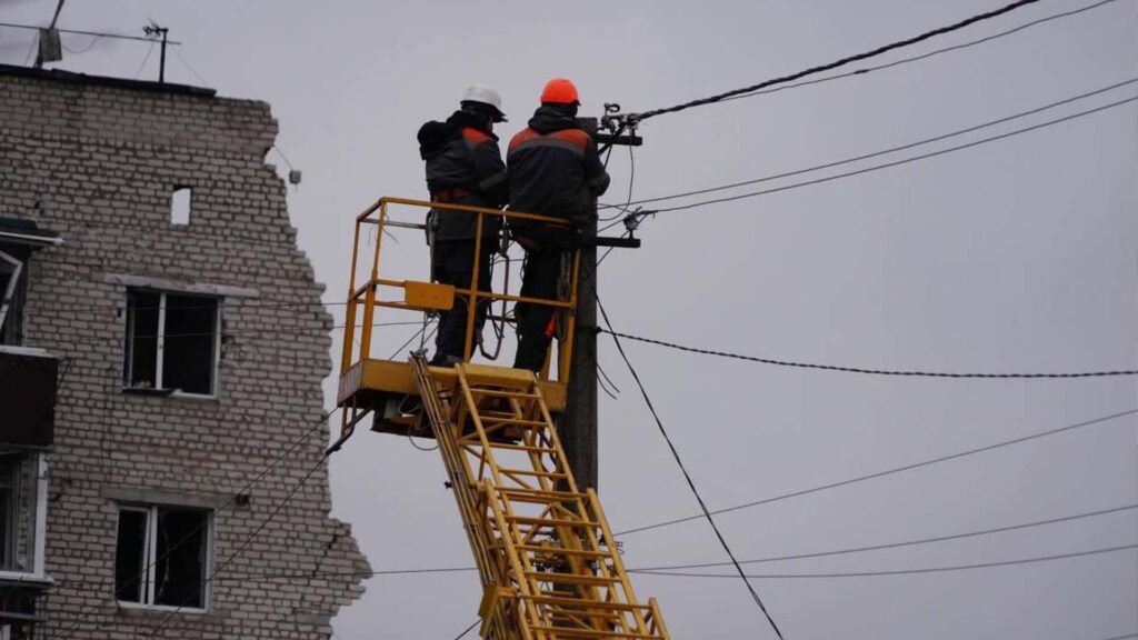 Двоє електриків на підйомнику проводять ремонт на електричному стовпі