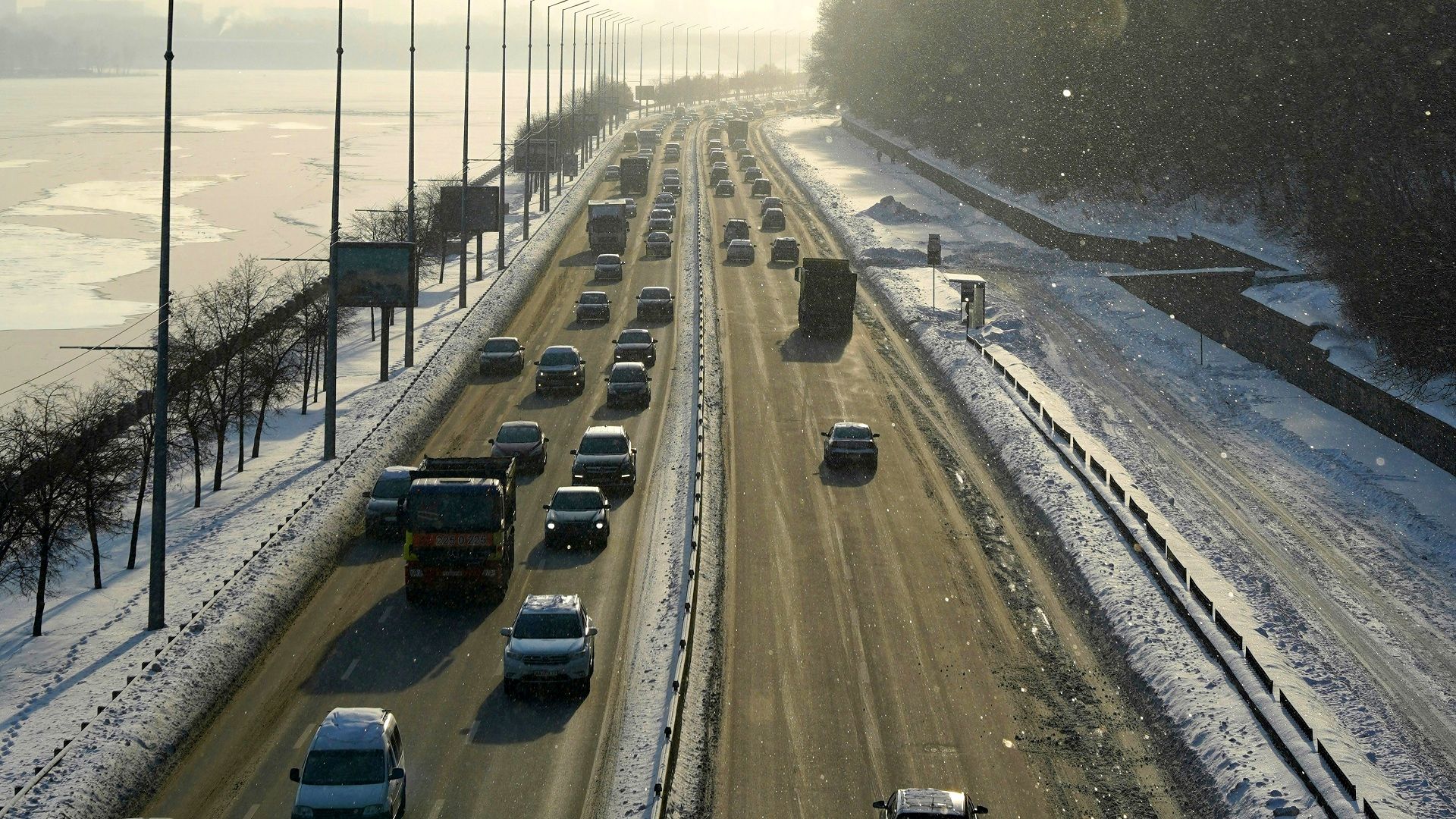 Зимова автомагістраль з інтенсивним рухом автомобілів під час снігопаду, засніжені узбіччя та обмежена видимість — ілюстрація до прогнозу погоди на Київщині