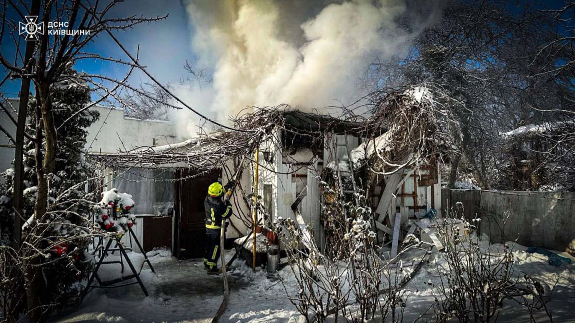 Пожежник гасить вогонь, який охопив невелику дерев'яну господарську споруду