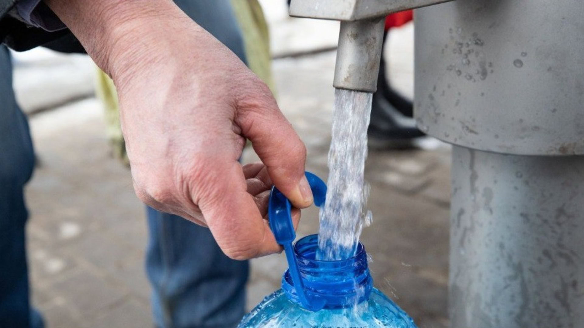 Чоловік набирає воду з артезіанської свердловини