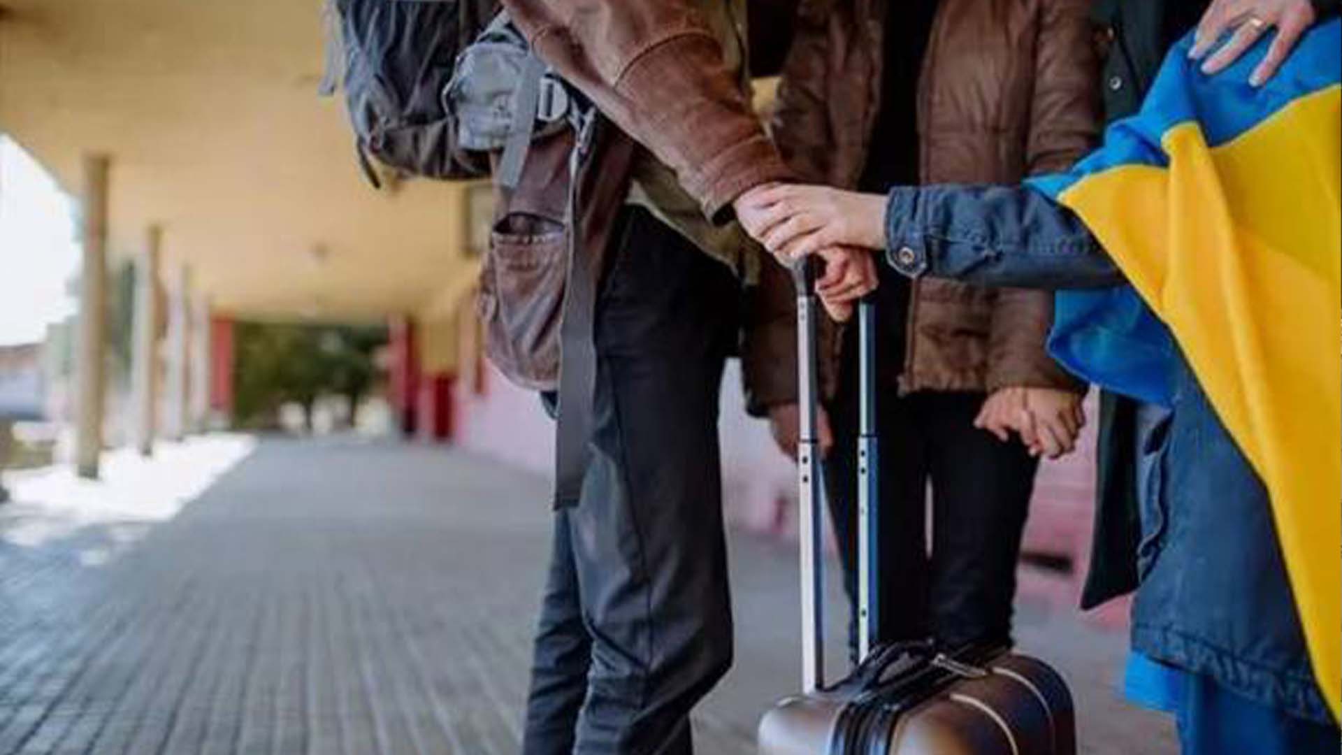 Троє людей з валізкою та українським прапором