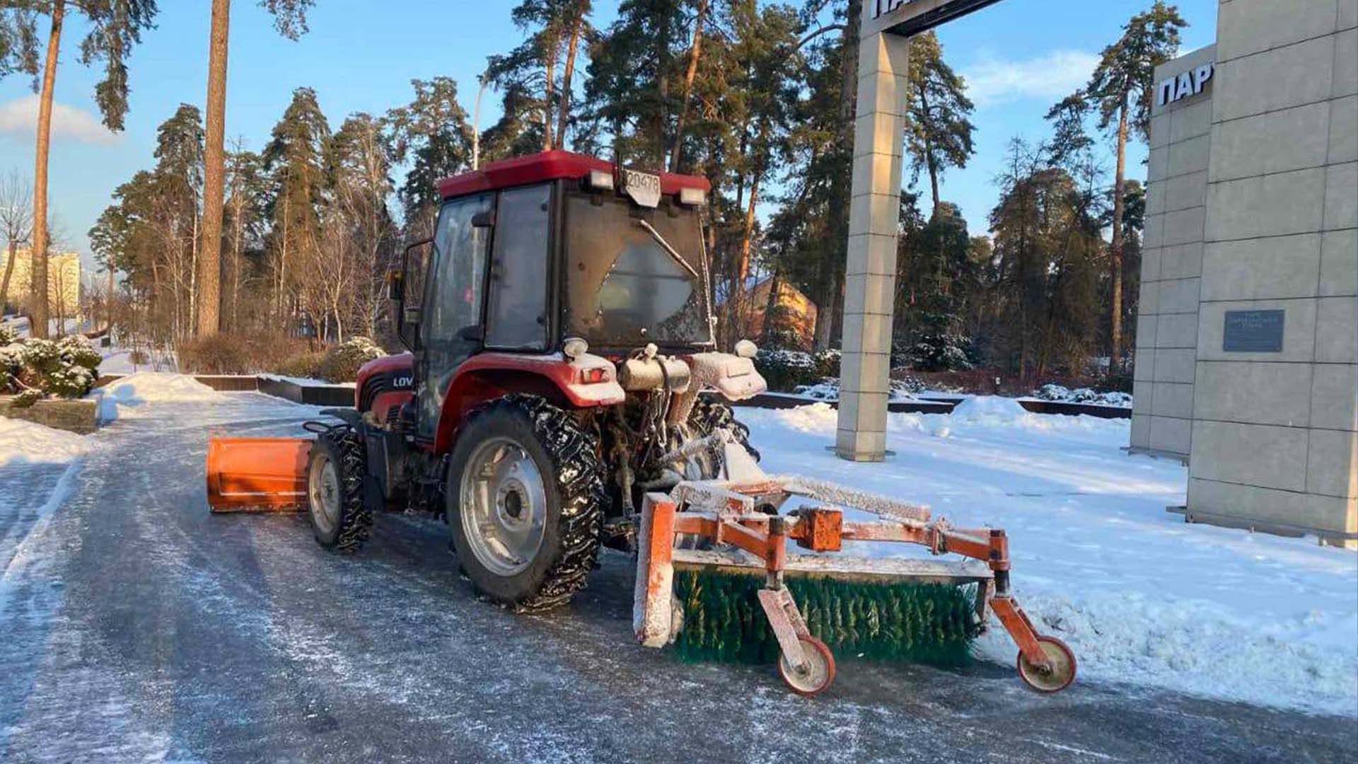 Трактор під час очищення снігу біля будівлі