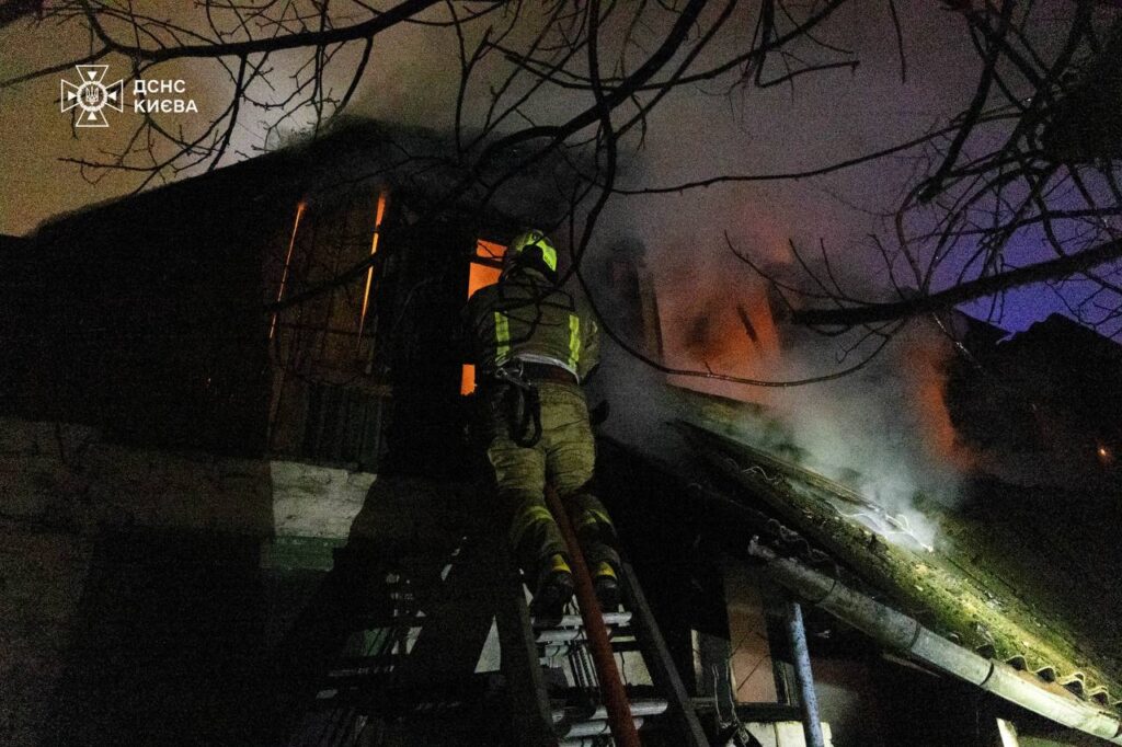 Пожежник на драбині на рівні другого поверху будинку