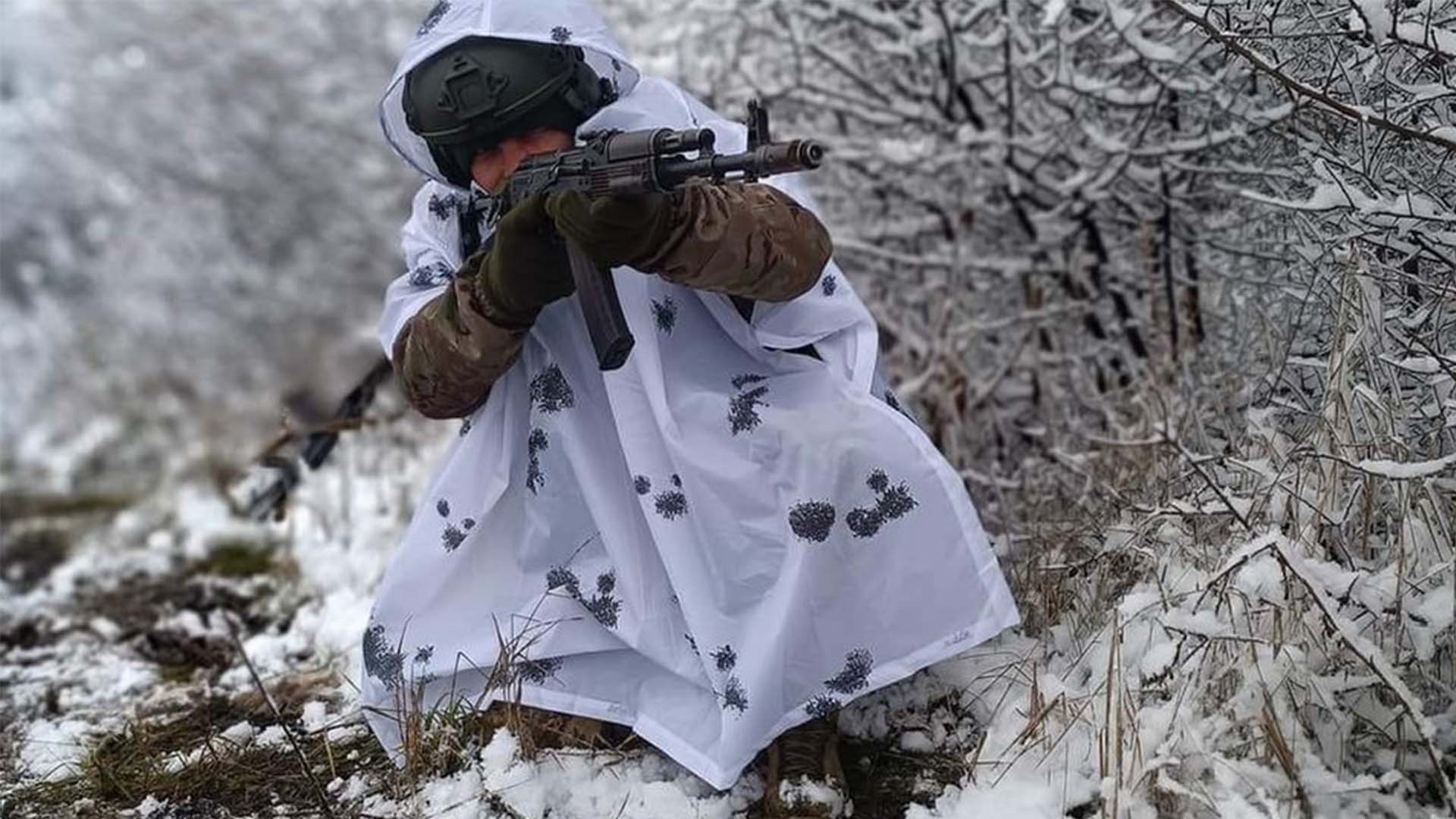 Солдат у білому маск-халаті прицілюється з гвинтівки