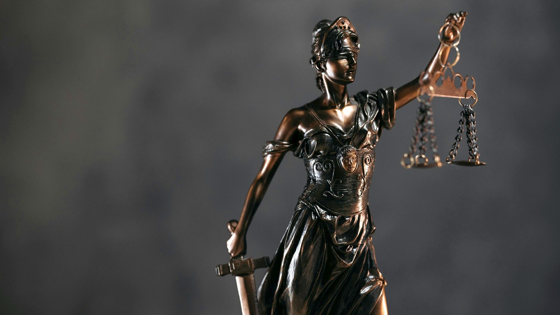 Статуетка богині Феміди з пов'язкою на очах і терезами правосуддя на столі, ілюстративне фото