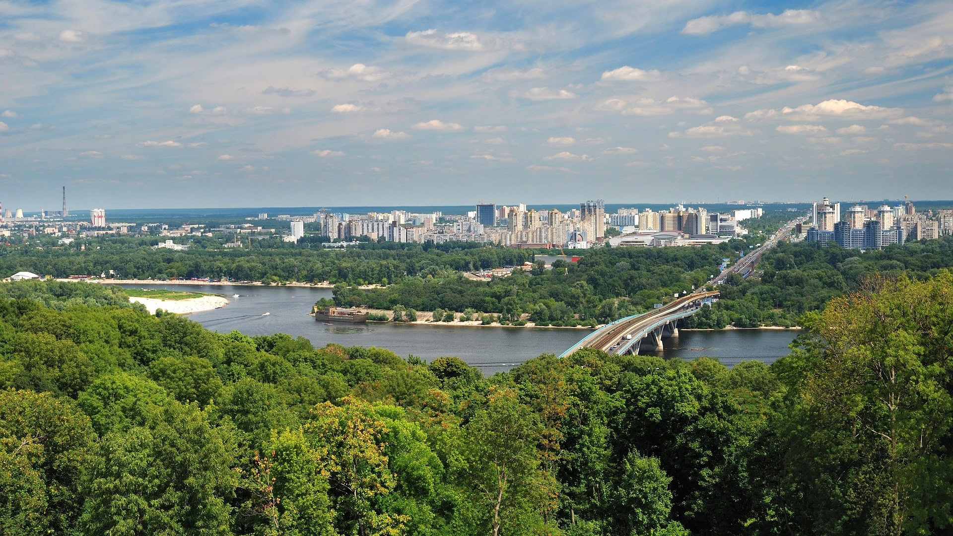Чому взимку важче дихати: що таке температурна інверсія і як вона впливає на повітря Аерофотознімок лівого берега Києва з Дніпром, мостом метро, історичними та сучасними будівлями