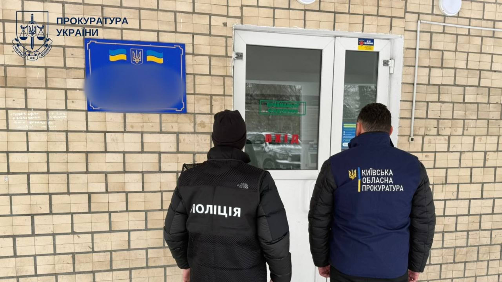 Двоє правоохоронців біля входу в офісну будівлю