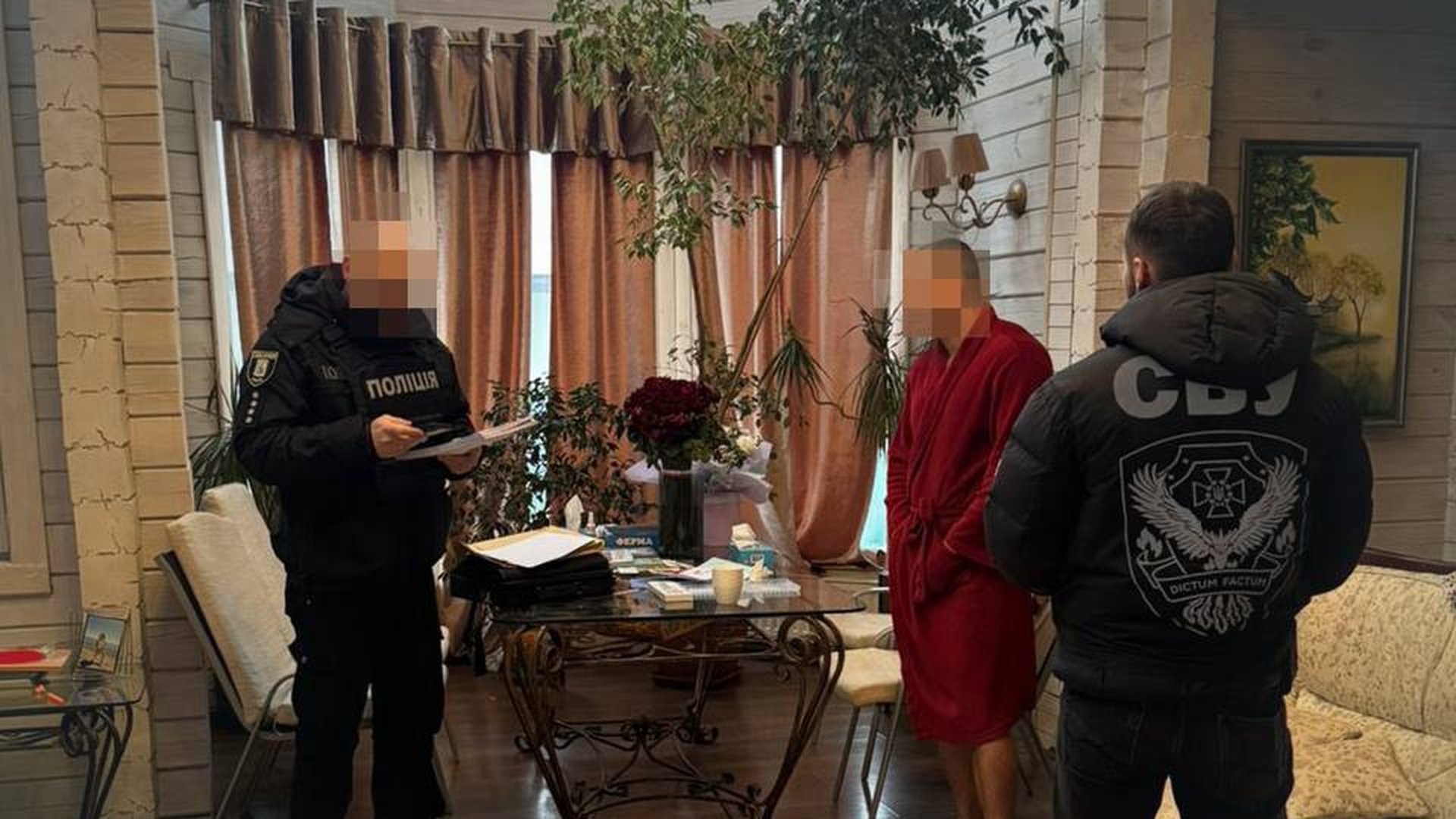 Співробітники СБУ та Національної поліції затримують підозрюваного у червоному халаті в житловому приміщенні, обличчя учасників заблюровані