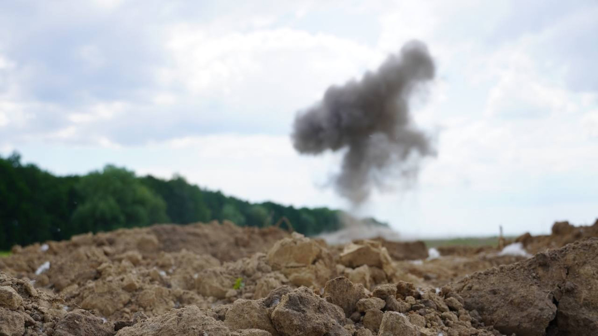 Стовп диму від планових вибухових робіт зі знищення боєприпасів на полі у Київській області