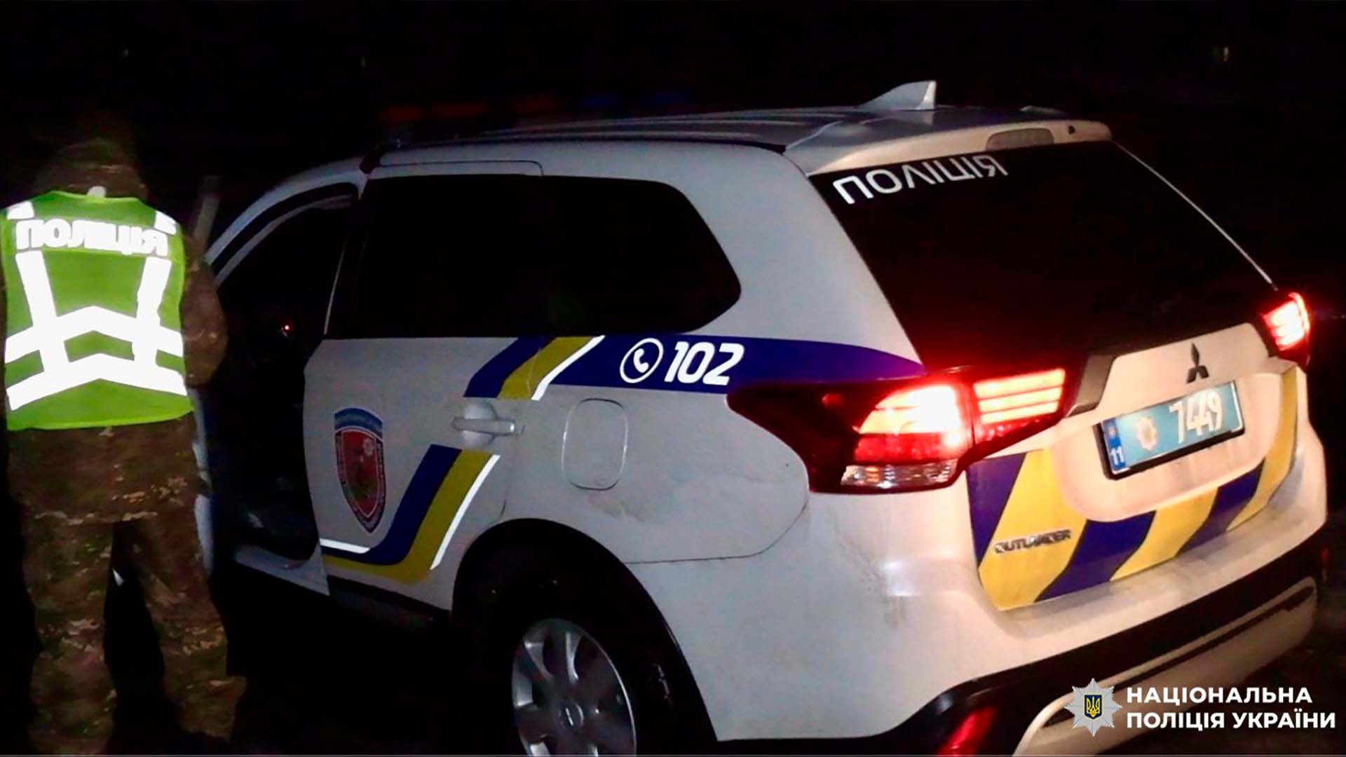 Поліцейський НПУ відкриває двері патрульного автомобіля