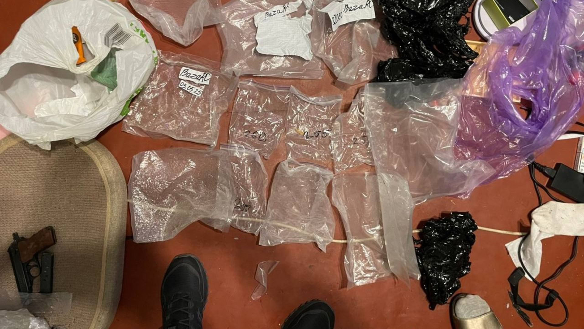 Вилучені речові докази у справі наркогрупи: пакети з психотропними речовинами, пістолет та інші предмети на підлозі