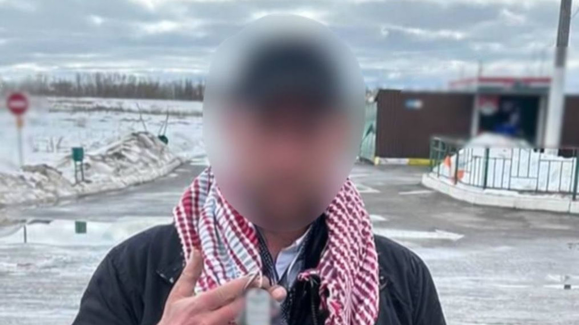 Затриманий чоловік із розмитим обличчям у чорній куртці та картатому шарфі на тлі засніженої території СТО в Броварах