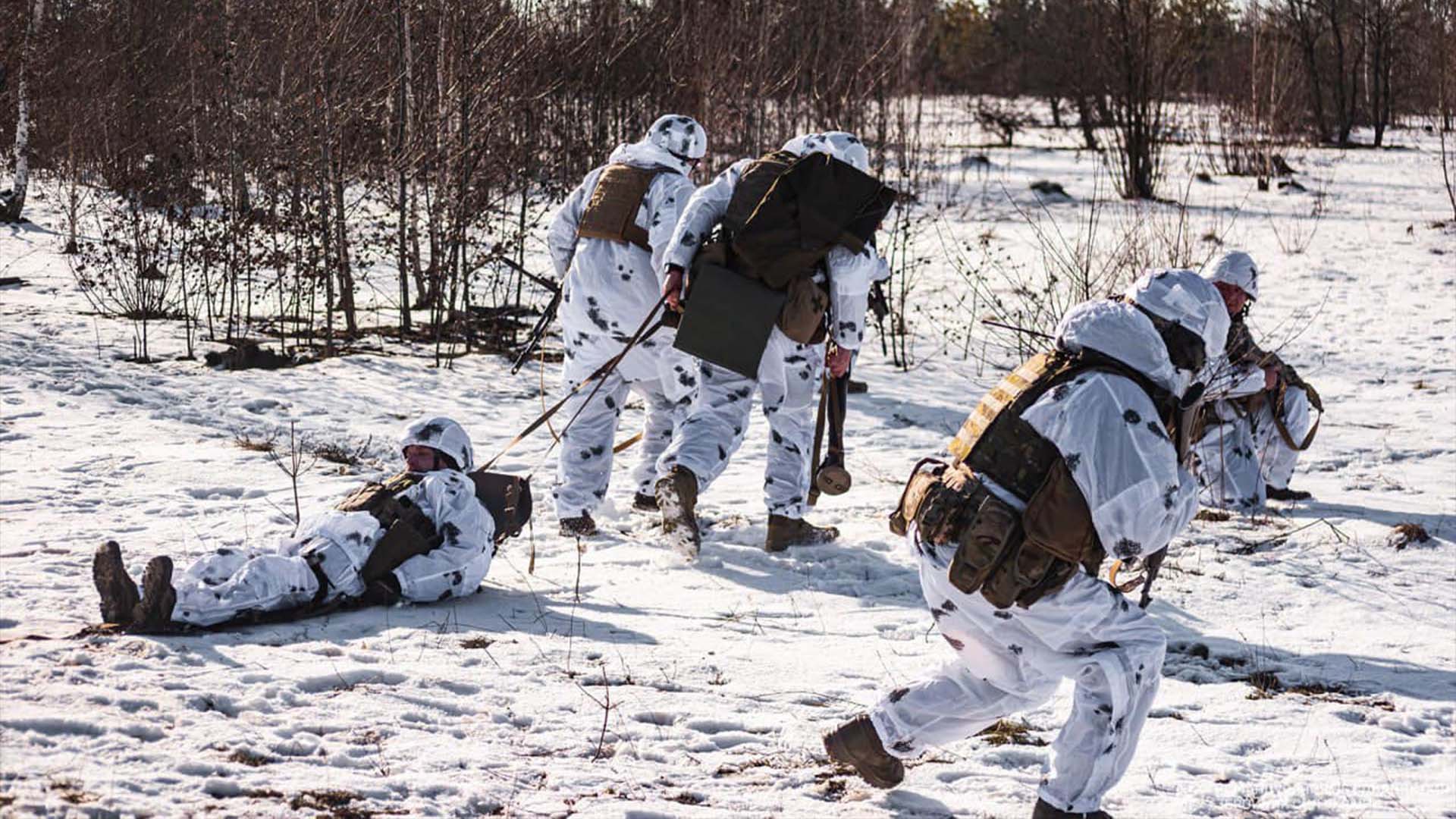 Українські військові у білих маскхалатах у лісовій місцевості