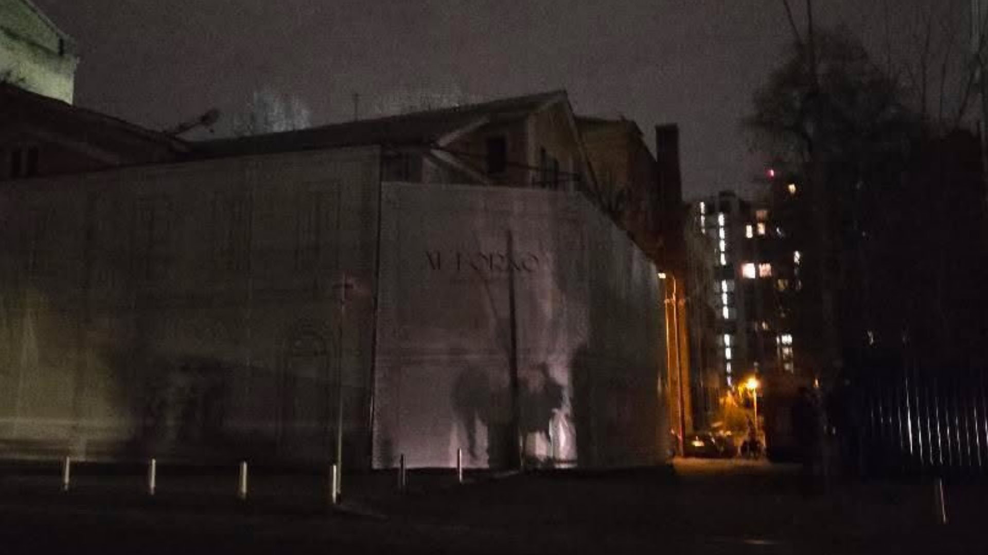 Будинок з Хлібною лавкою на Ярославовому Валу вночі закритий банером із намальованим фасадом