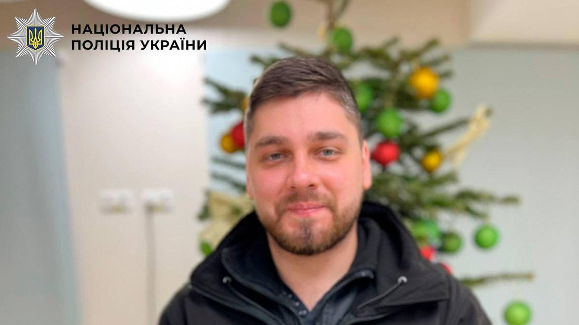 Поліцейський Олександр Дідушко з Шевченківського управління поліції Києва тримає посвідчення «Почесний донор України» на фоні новорічної ялинки