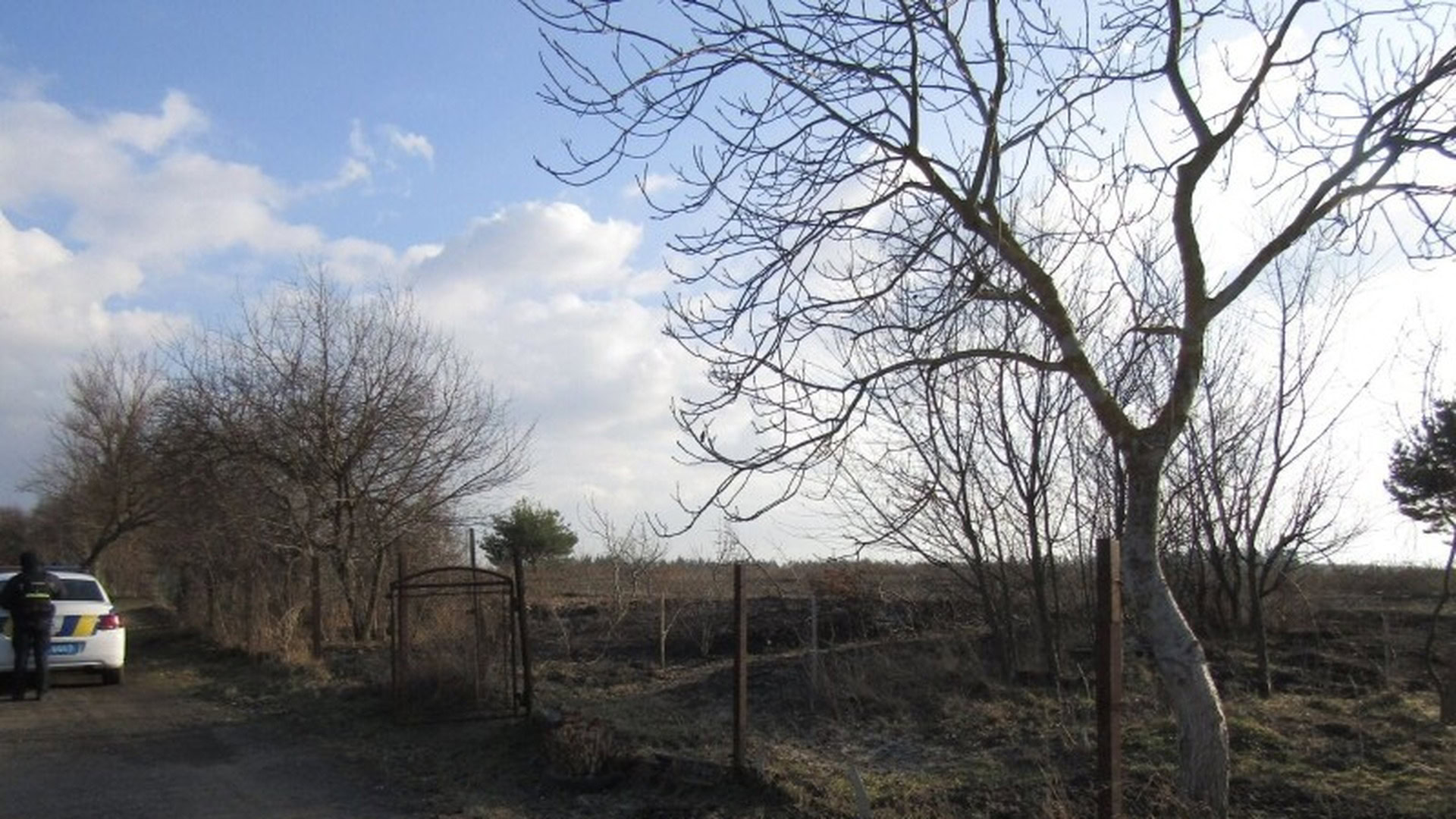 Поліцейське авто біля обгорілої ділянки у Ясногородці Фастівського району, де загинув 66-річний чоловік