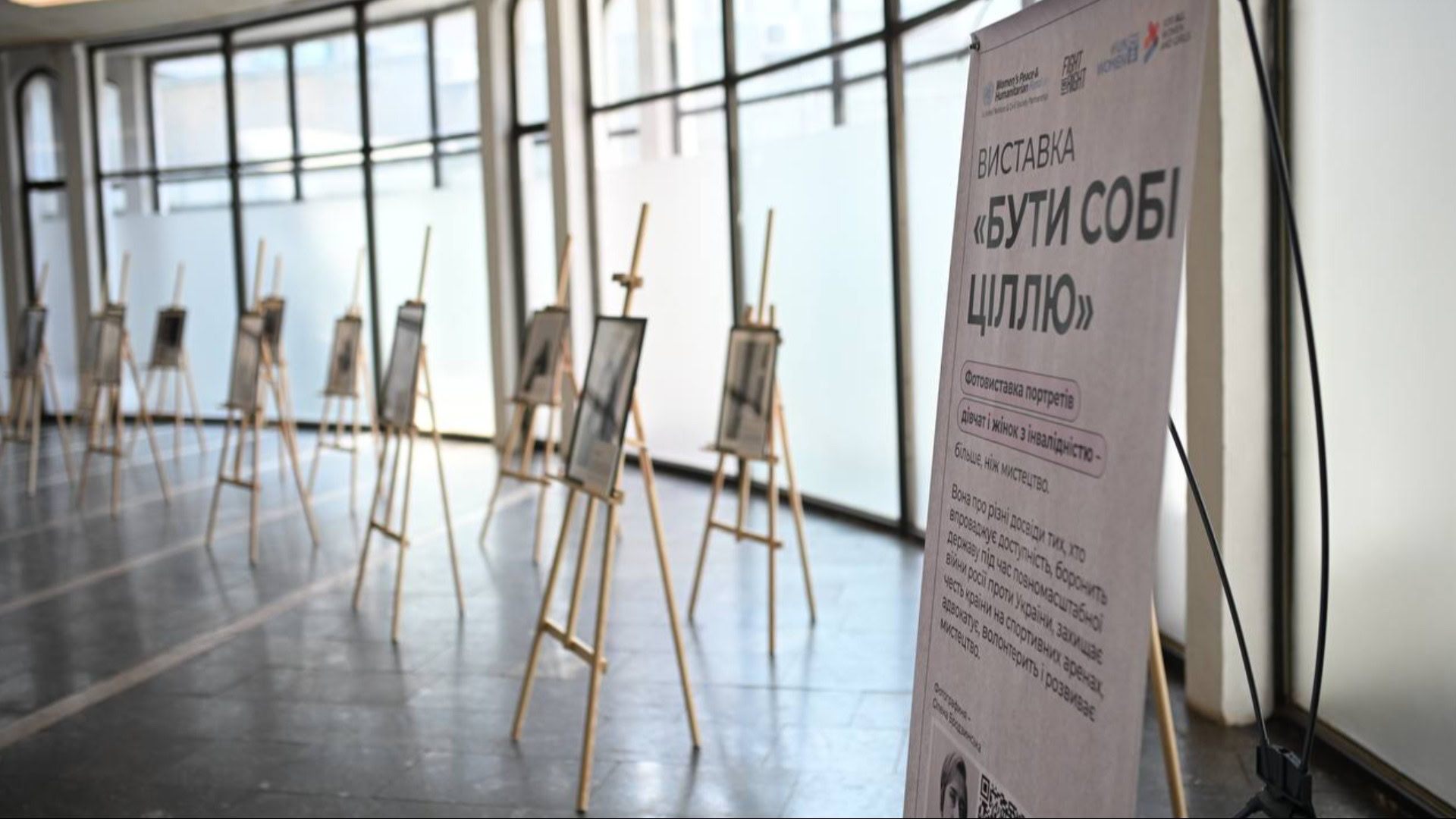Фотовиставка «Бути собі ціллю» у вестибюлі станції метро «Золоті ворота» в Києві: портрети на мольбертах та інформаційний банер