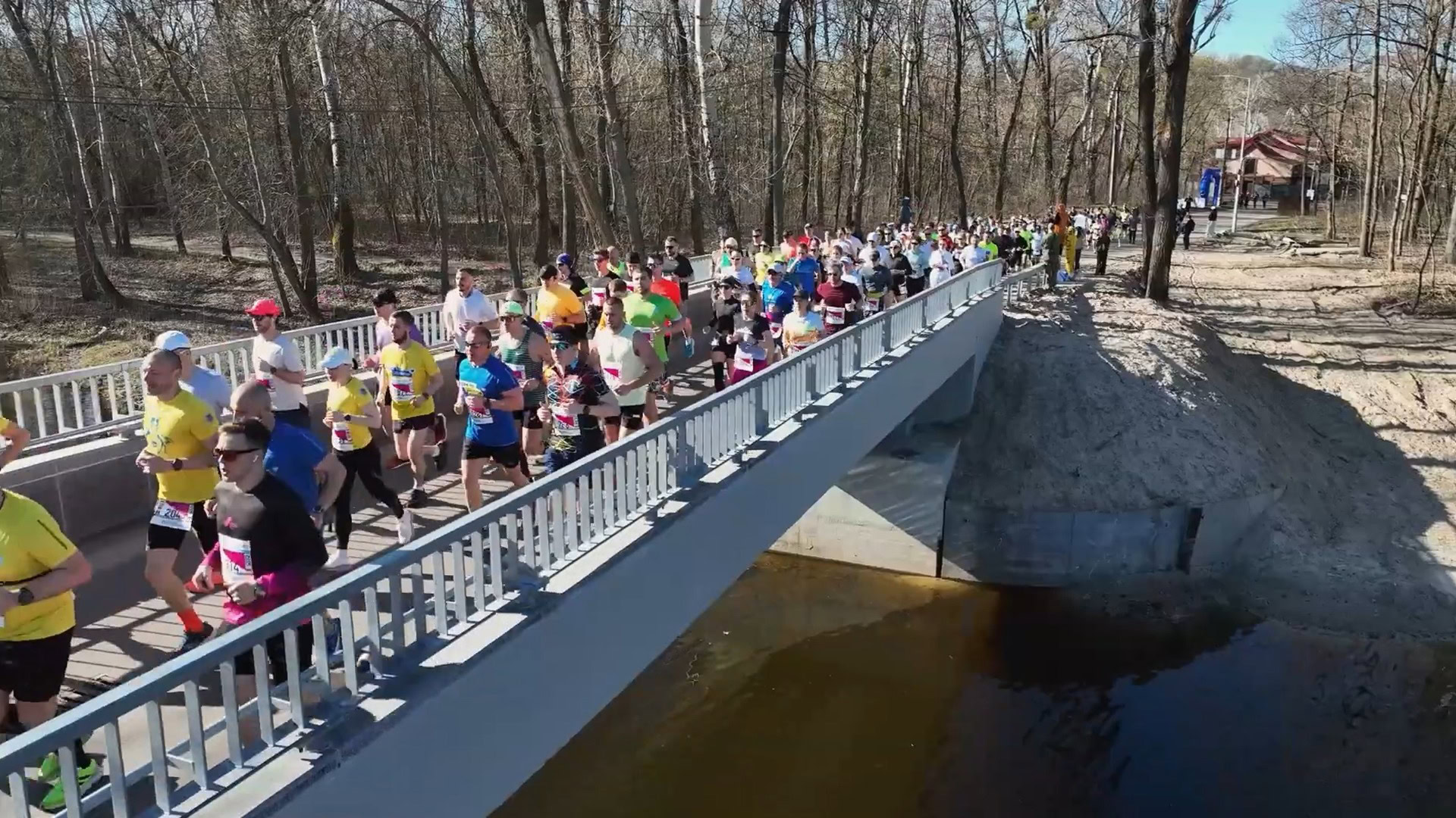 Учасники 15-го Київського півмарафону Незламності 2026 біжать мостом у парковій зоні Києва