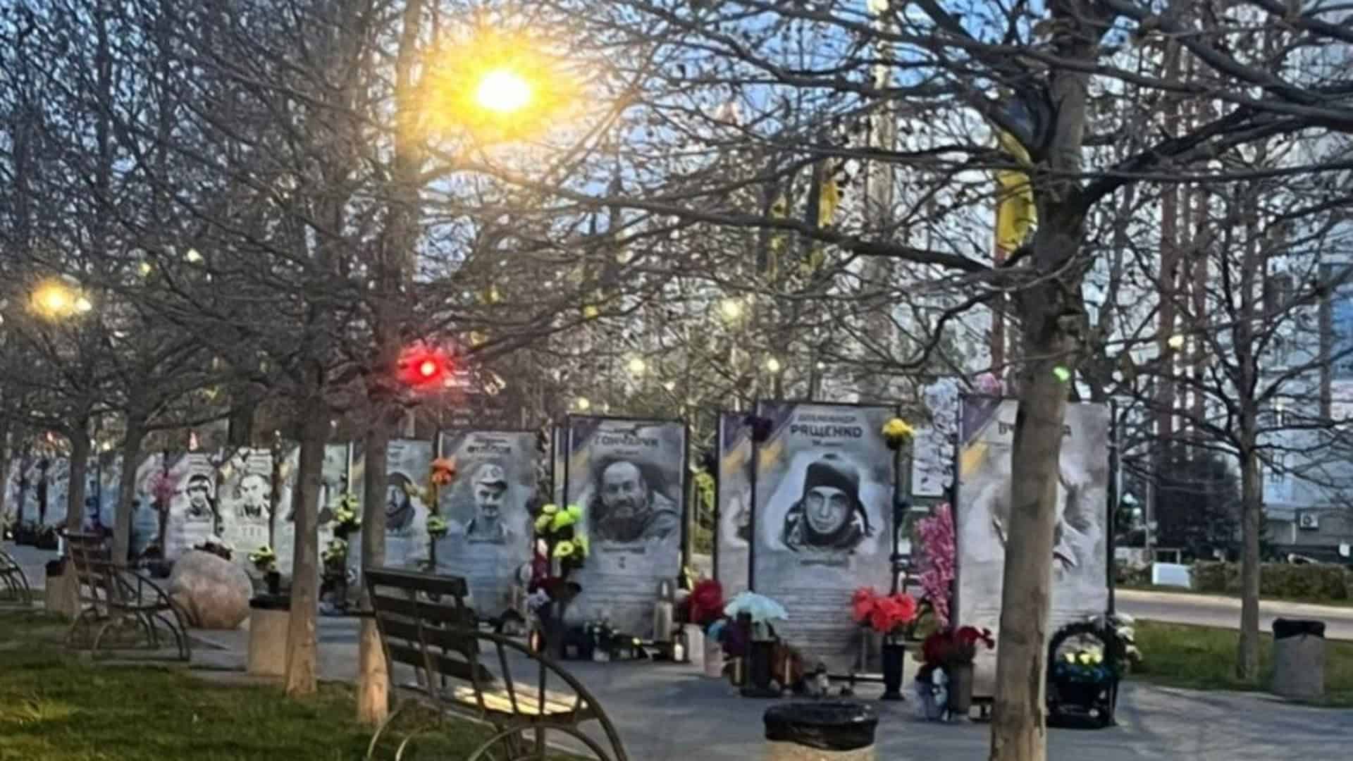 Алея пам'яті Героїв в Обухові — портрети загиблих захисників з квітами біля меморіалу на вулиці міста увечері