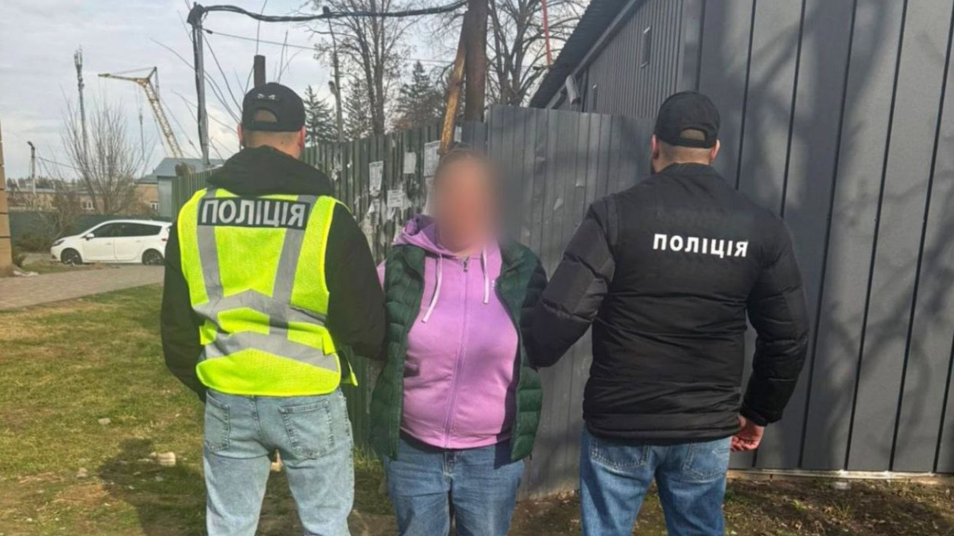 Поліцейські у формі тримають затриману жінку біля паркану у Вишневому, підозра у впливі на рішення ТЦК