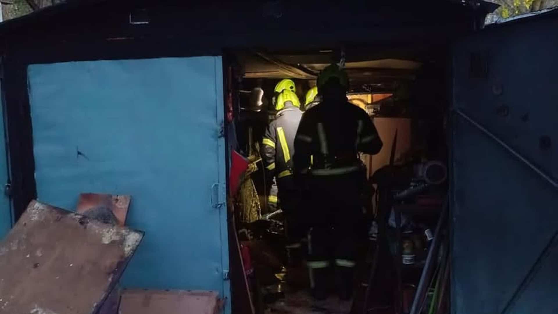 Рятувальники ДСНС Києва в спорядженні гасять пожежу всередині металевого гаражу на вулиці Червонопільській у Подільському районі