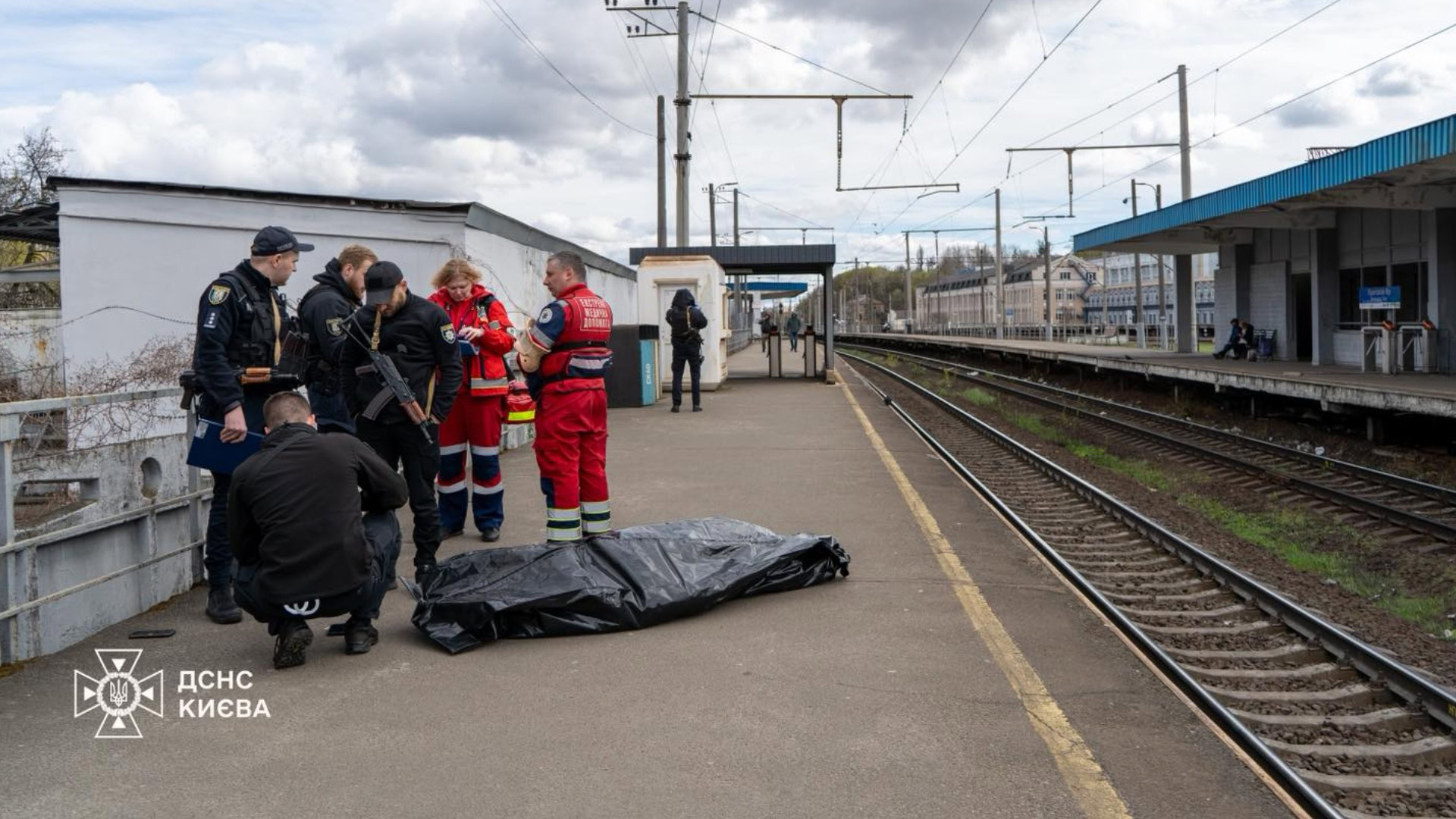 Рятувальники ДСНС та поліцейські на платформі електропотяга в Солом'янському районі Києва піднімають тіло загиблого чоловіка