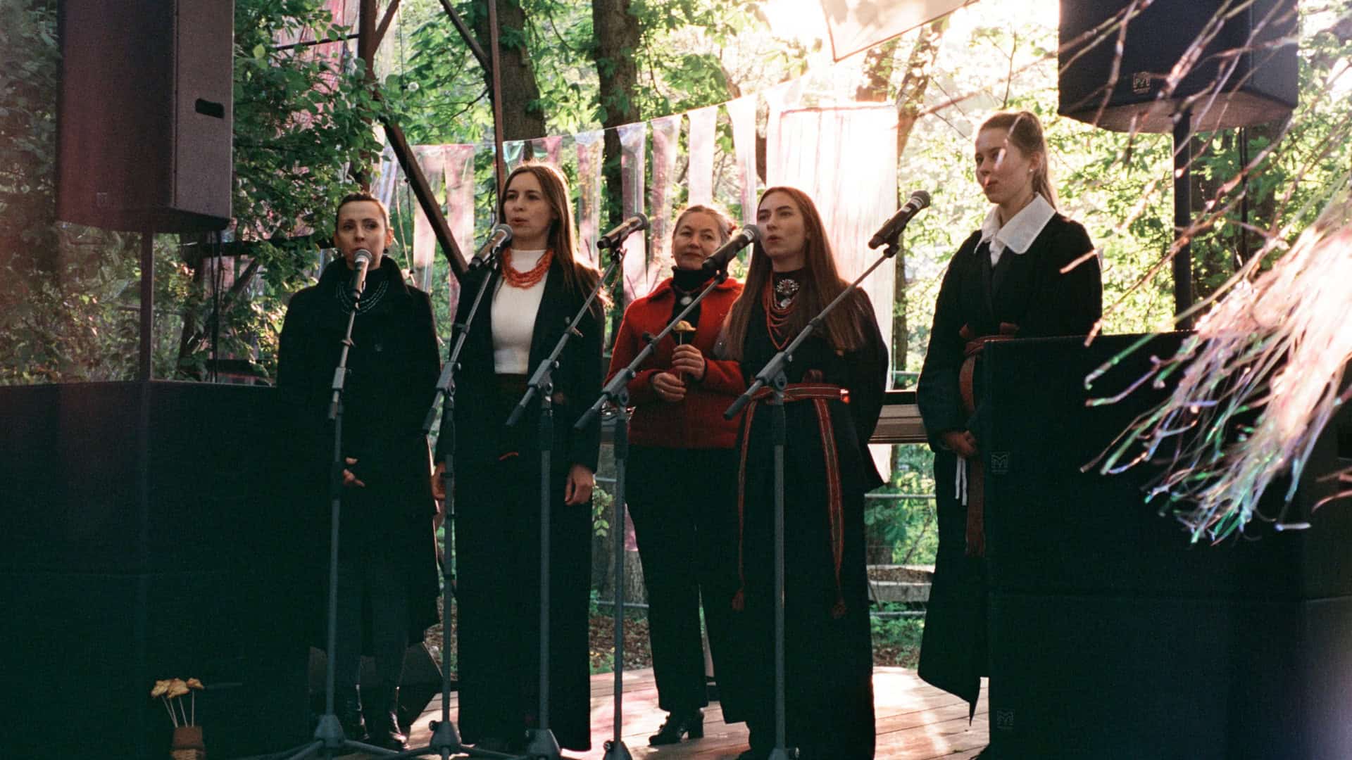 П'ять співачок у темному одязі з намистом і рушниками співають у мікрофони на сцені концерту СМИК.Весна в Києві