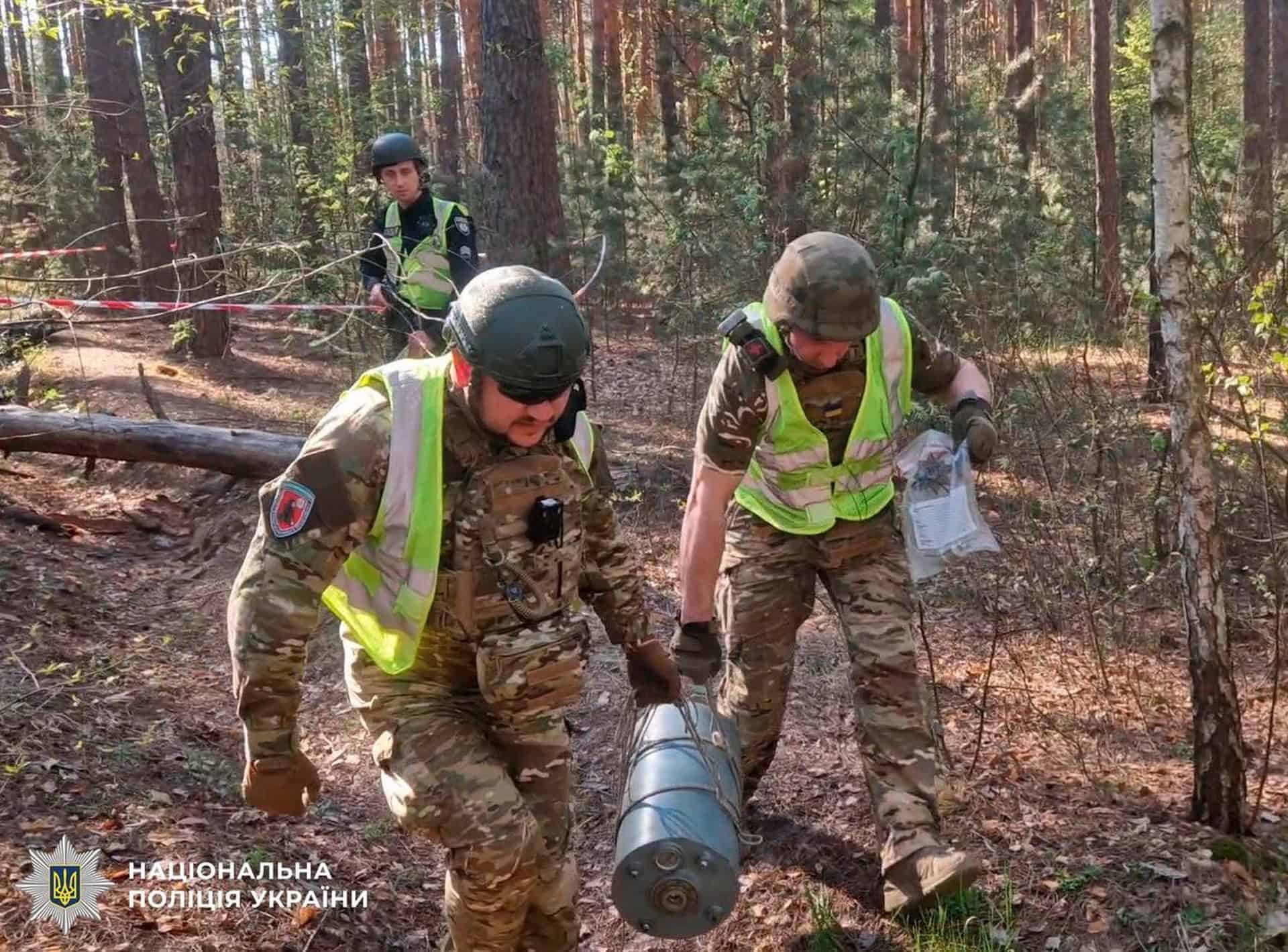Вибухотехніки поліції у захисних жилетах і шоломах виносять бойову частину дрона Герань-2 з лісосмуги Деснянського району Києва