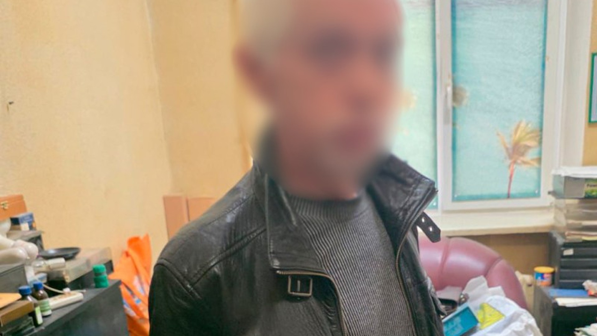 Чоловік у чорній шкіряній куртці з розмитим обличчям у поліцейському відділку — підозрюваний у розгромі кав'ярні у Шевченківському районі Києва