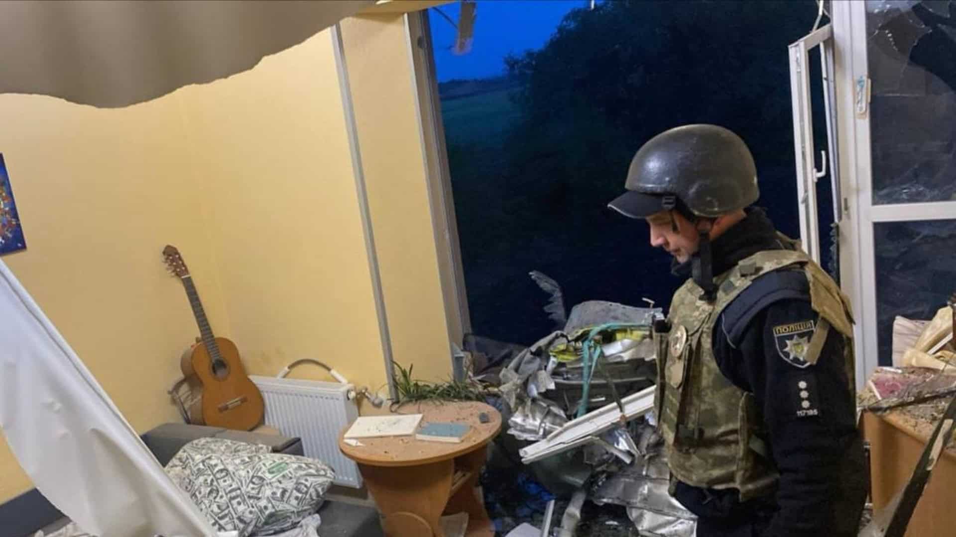 Поліцейський у бронежилеті та шоломі оглядає зруйновану кімнату приватного будинку після ракетного удару на Київщині 14 травня 2026 року
