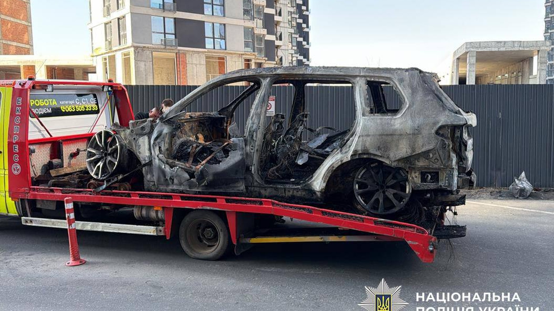 Повністю знищений вогнем BMW X7 на евакуаторі після підпалу на підземному паркінгу у Дарницькому районі Києва