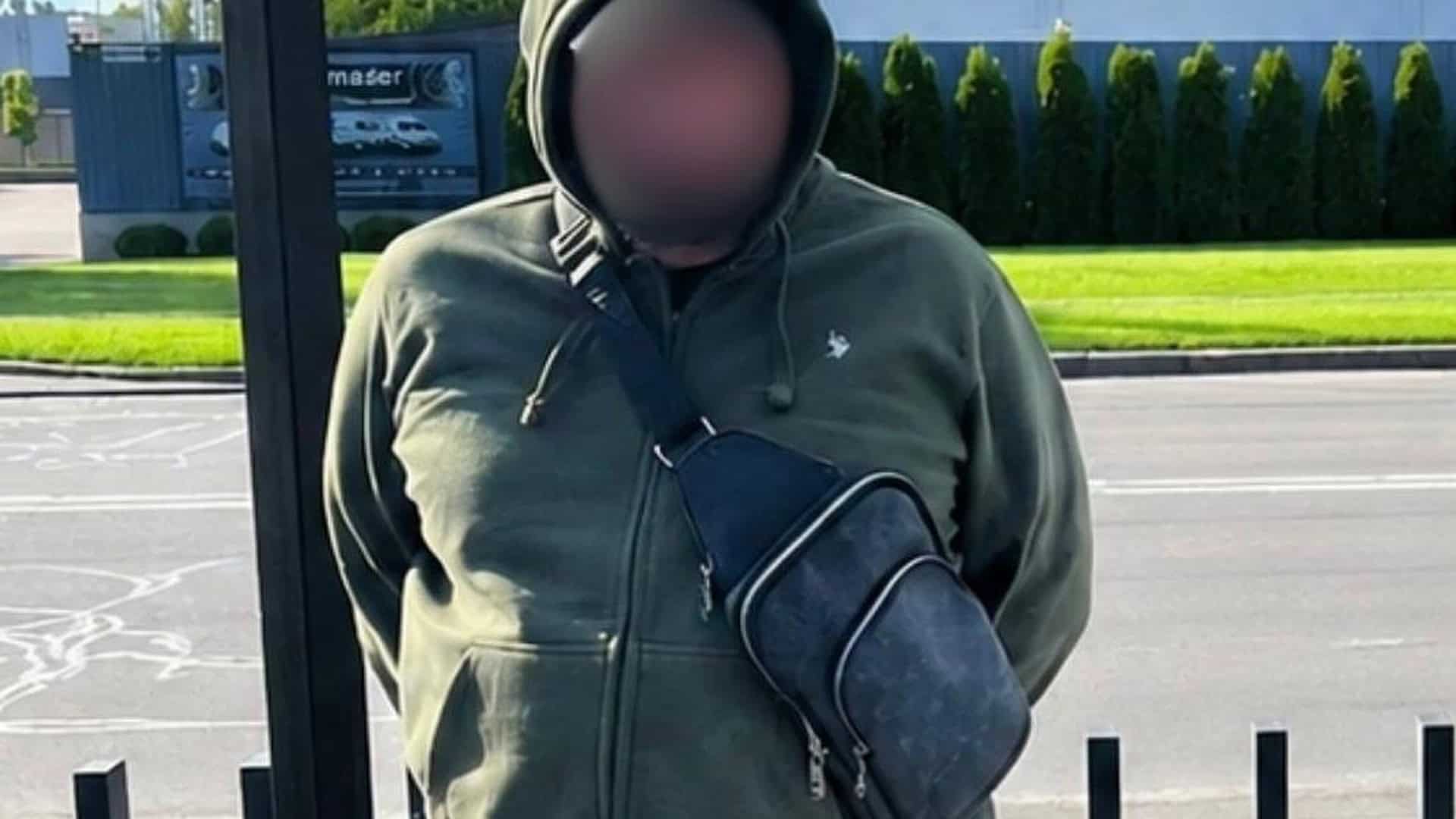 Чоловік у зеленому худі з сумкою через плече — підозрюваний директор благодійної організації, якого затримала прокуратура