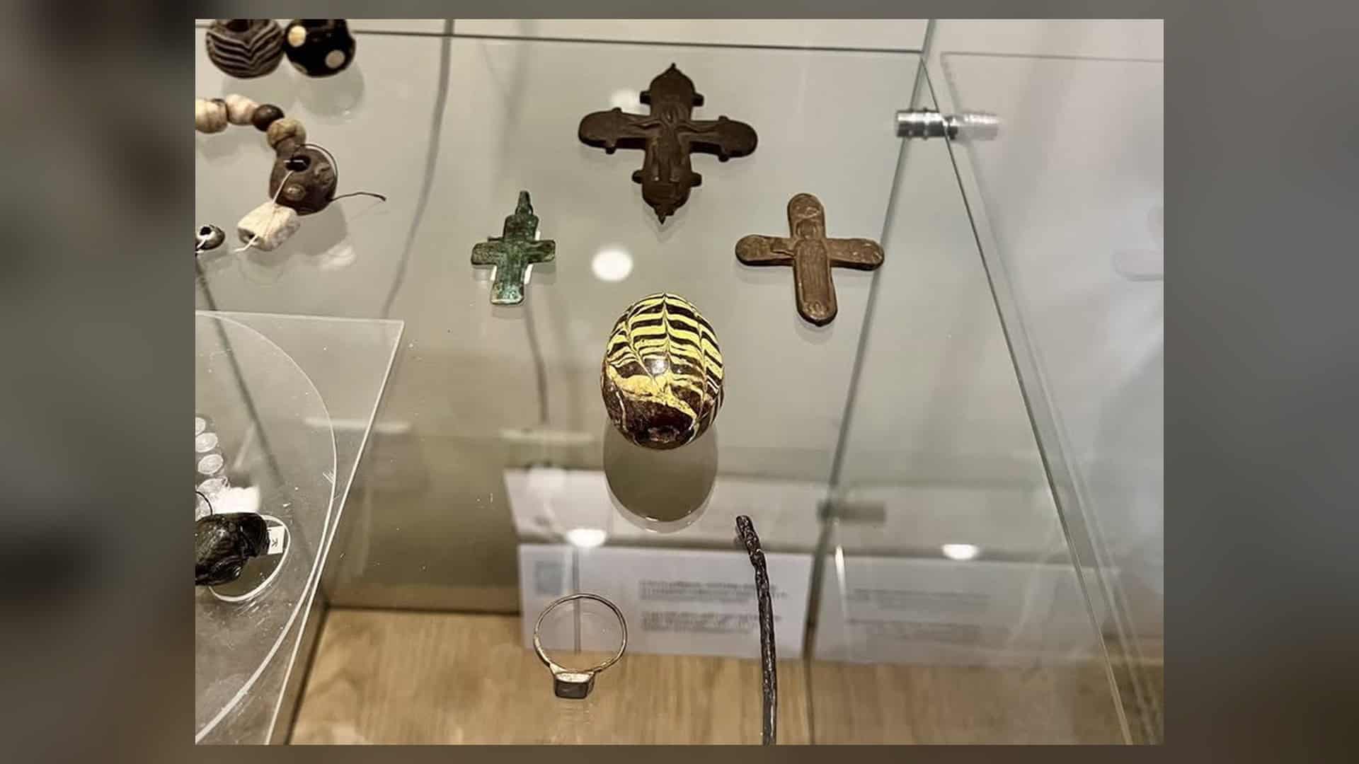 Керамічна полив'яна писанка-брязкальце XII століття поряд із давніми хрестиками та перснем у вітрині Брами Заборовського — Національний заповідник «Софія Київська»
